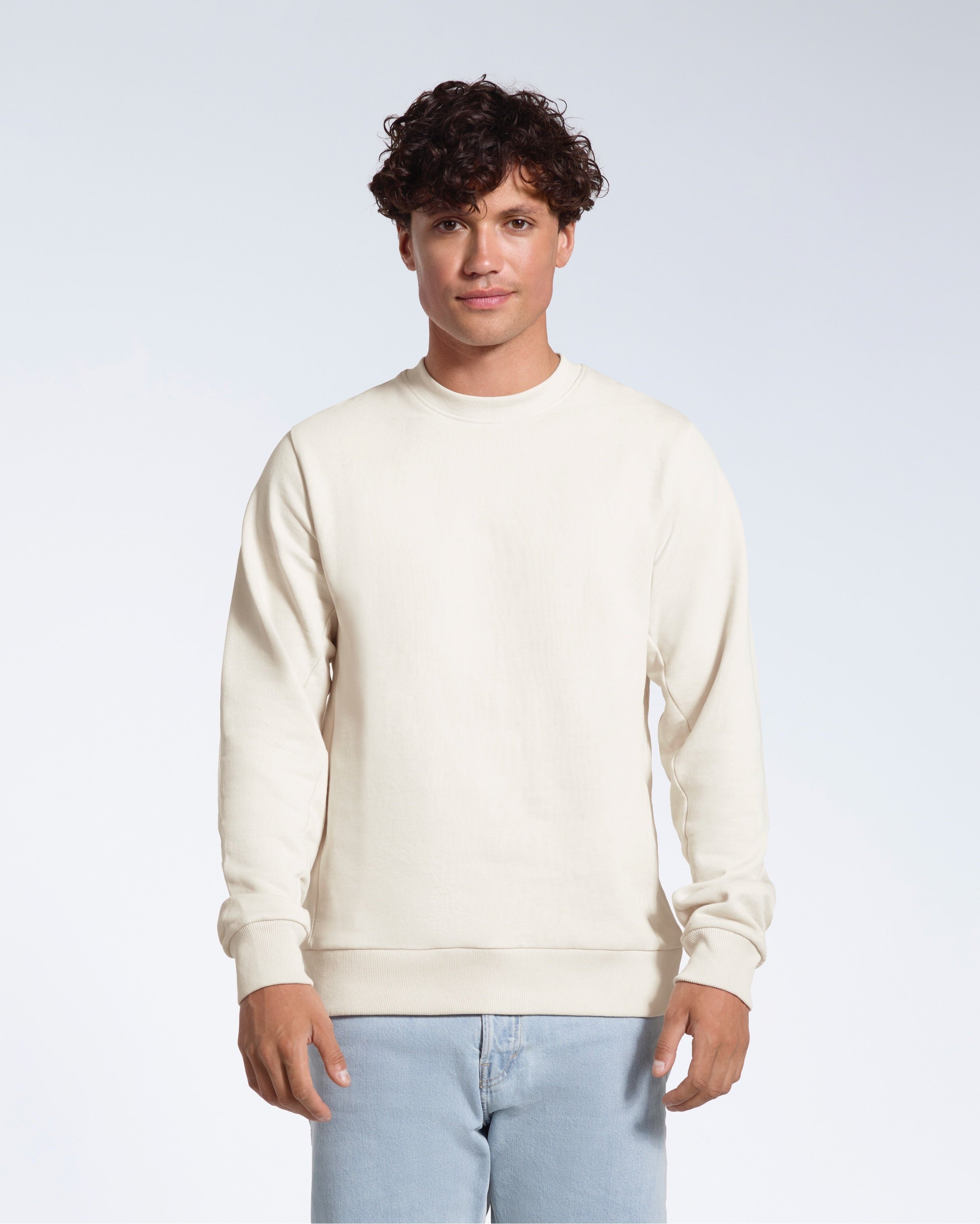 A man face on looking into the camera with his arms by his side, modelling a plain off white french terry organic cotton sweatshirt.