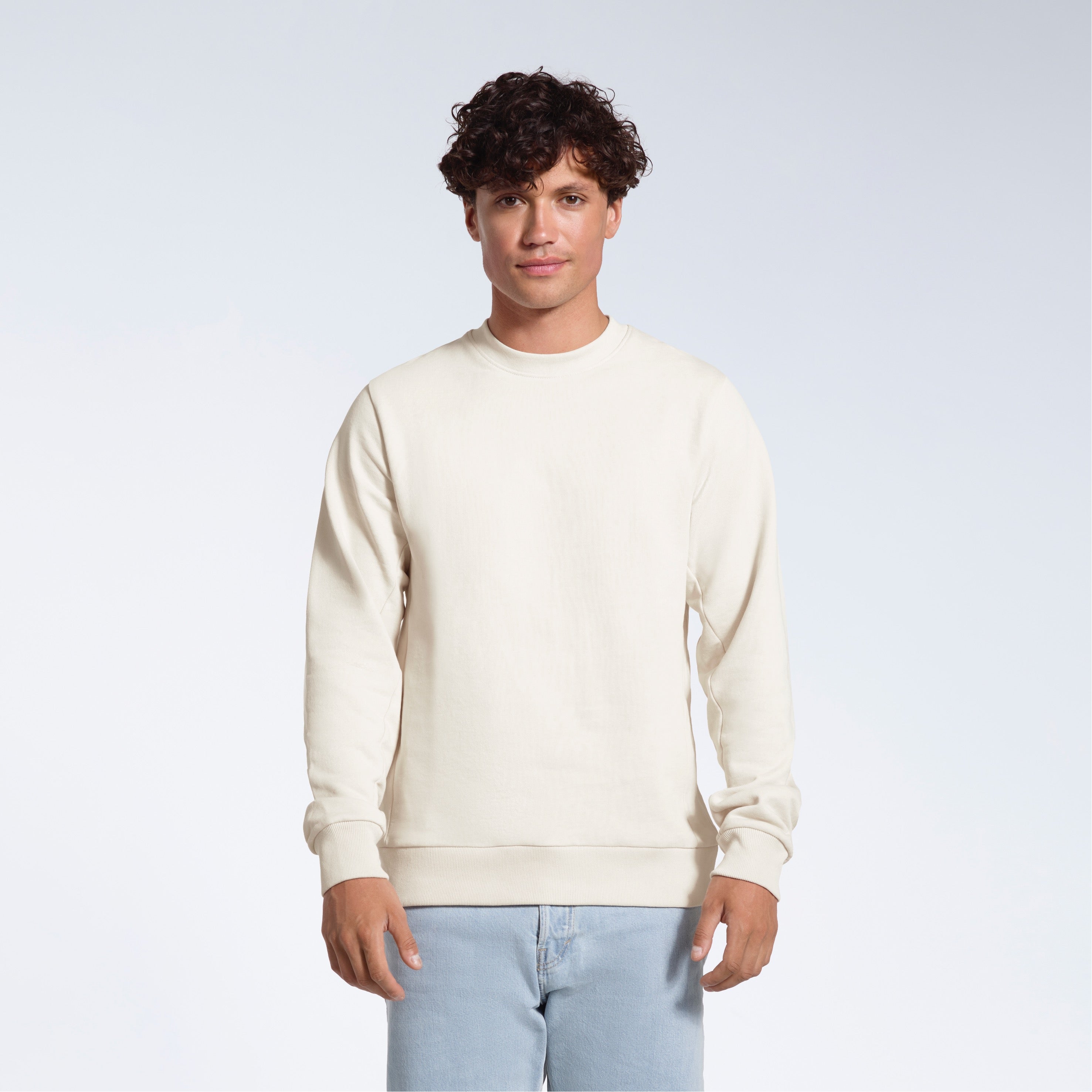 A man face on looking into the camera with his arms by his side, modelling a plain off white french terry organic cotton sweatshirt.