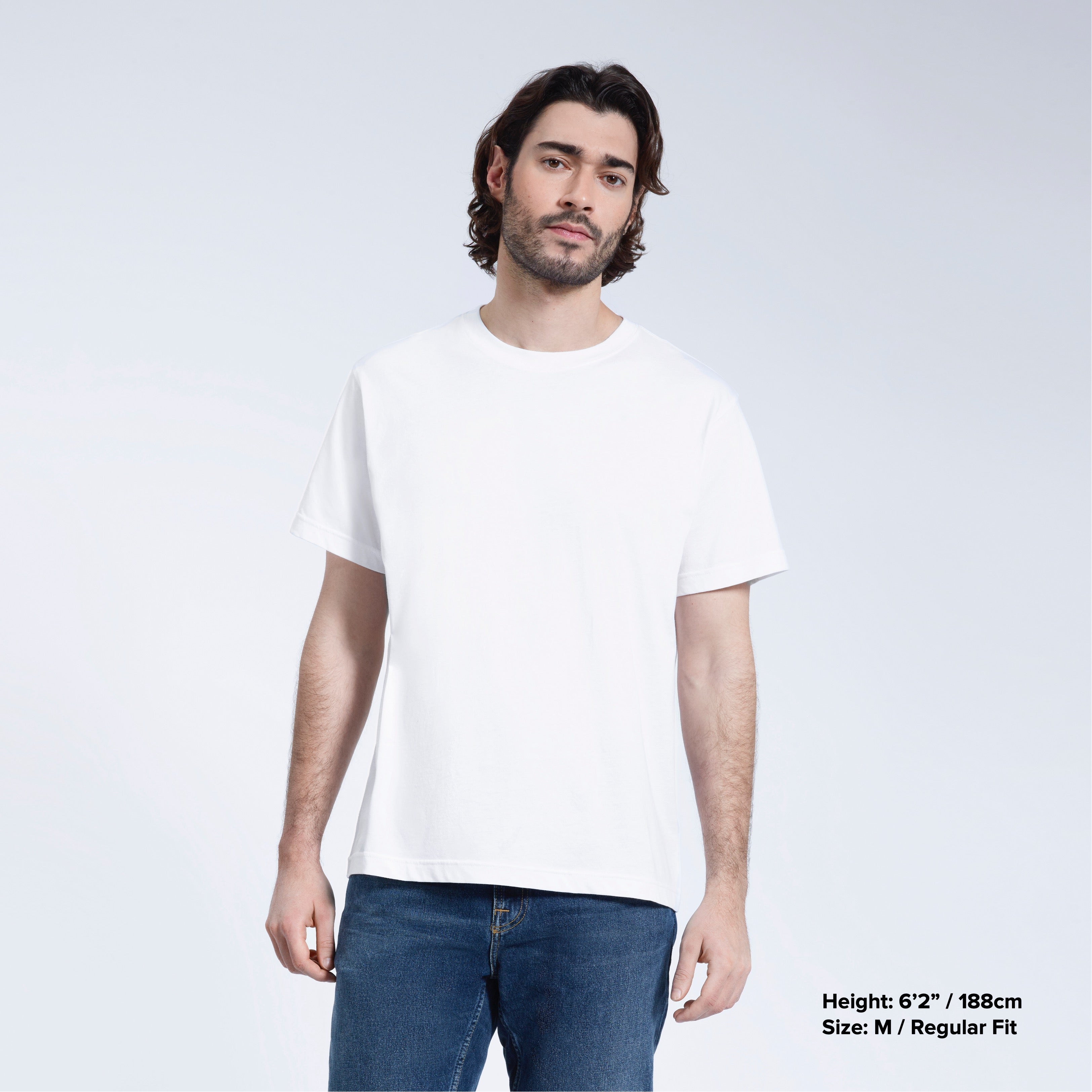A man face on looking into the camera with his arms by his sides, modelling a plain white short sleeve organic cotton t shirt.