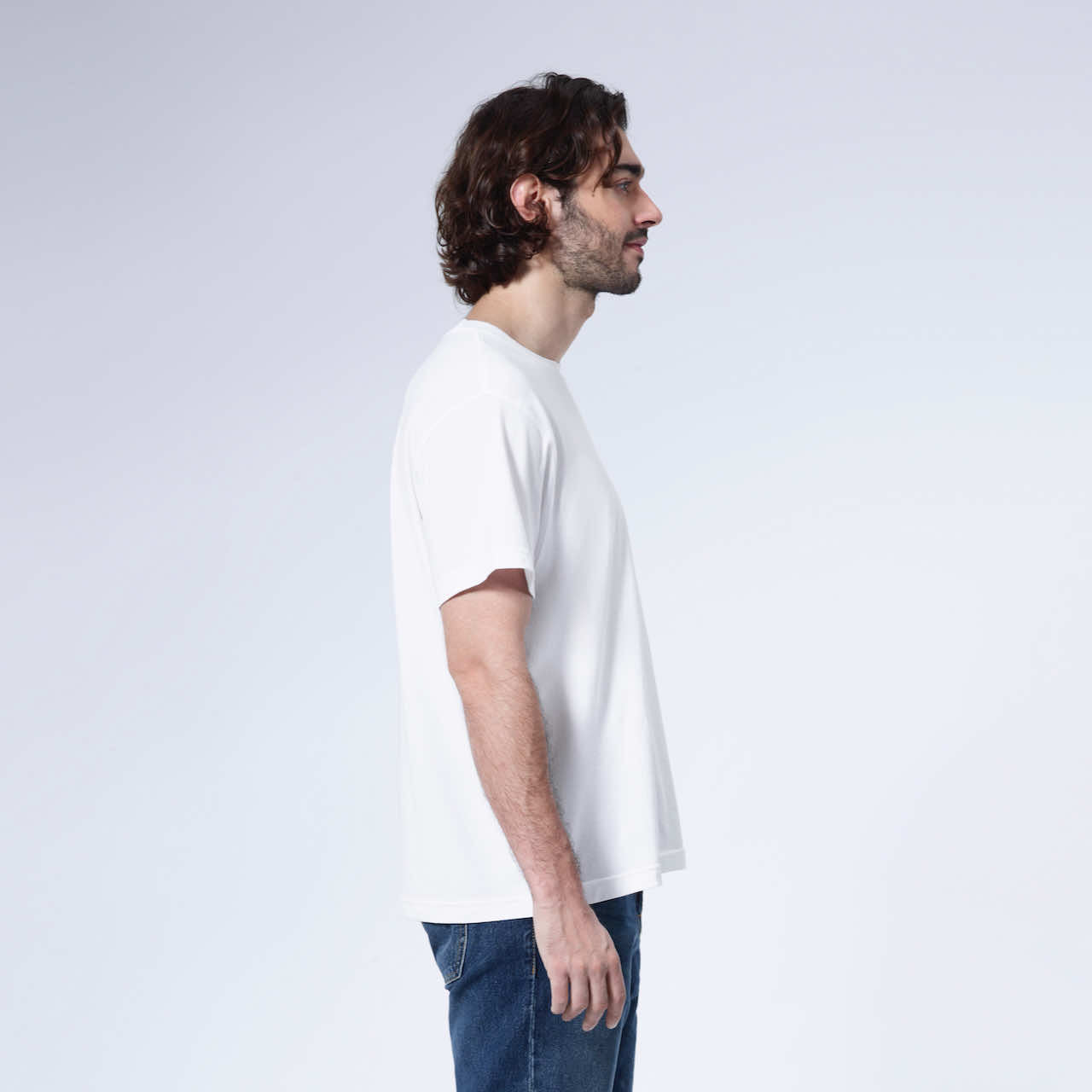 A man facing side on, modelling a plain white short sleeve organic cotton t shirt.