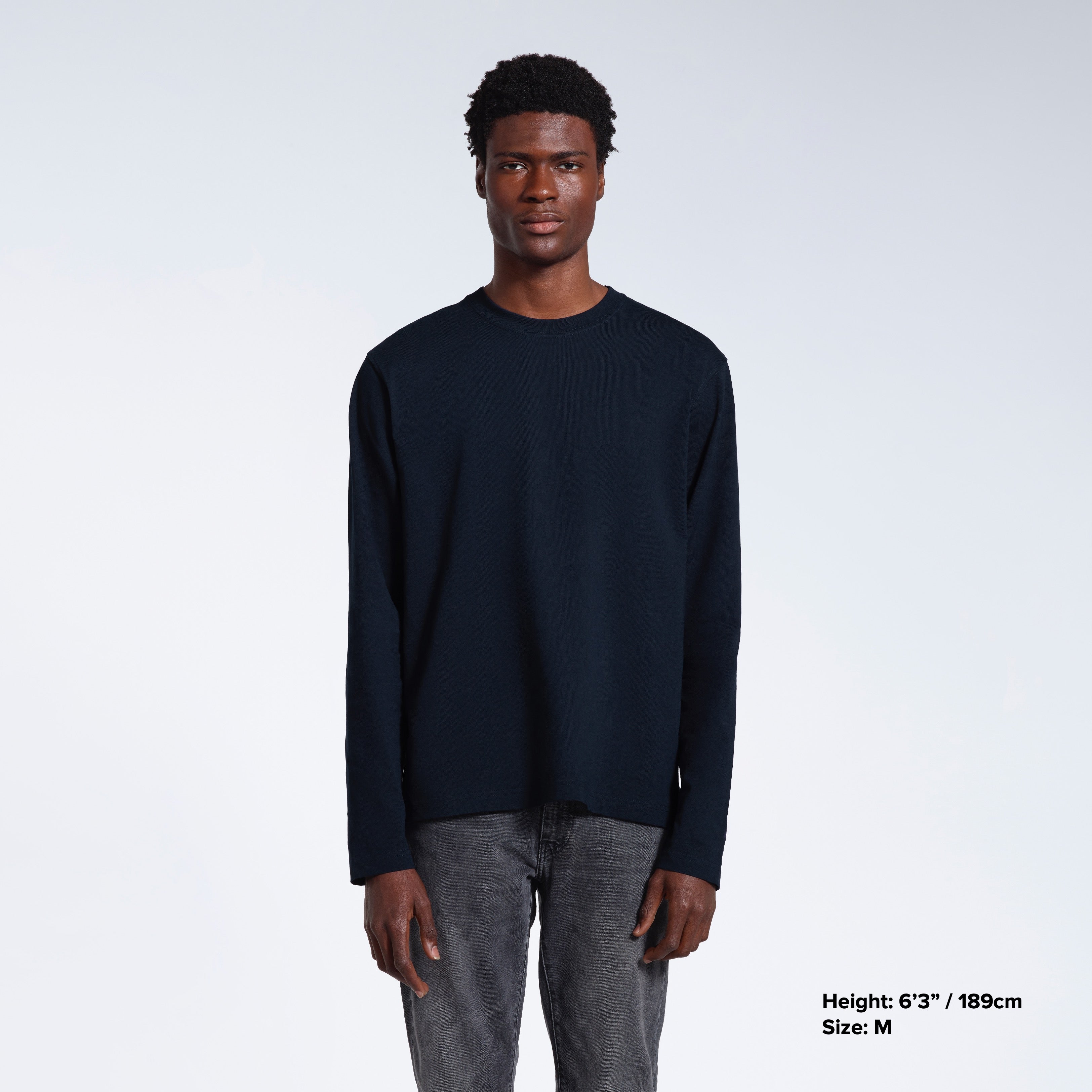 A man standing front on with his arms by his sides, modelling a plain navy long sleeve organic cotton t shirt.