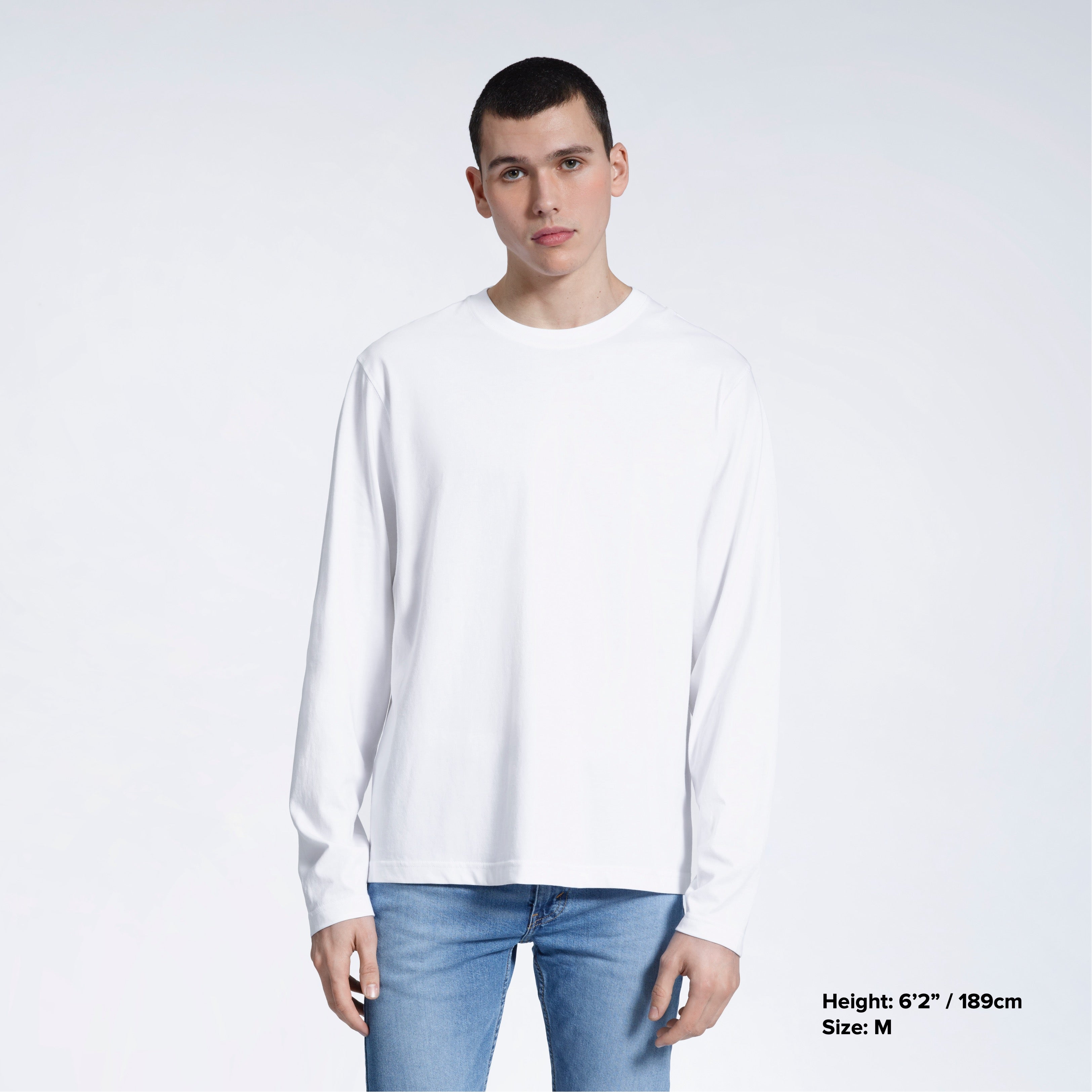 A man standing front on with his arms by his sides, modelling a plain white long sleeve organic cotton t shirt.