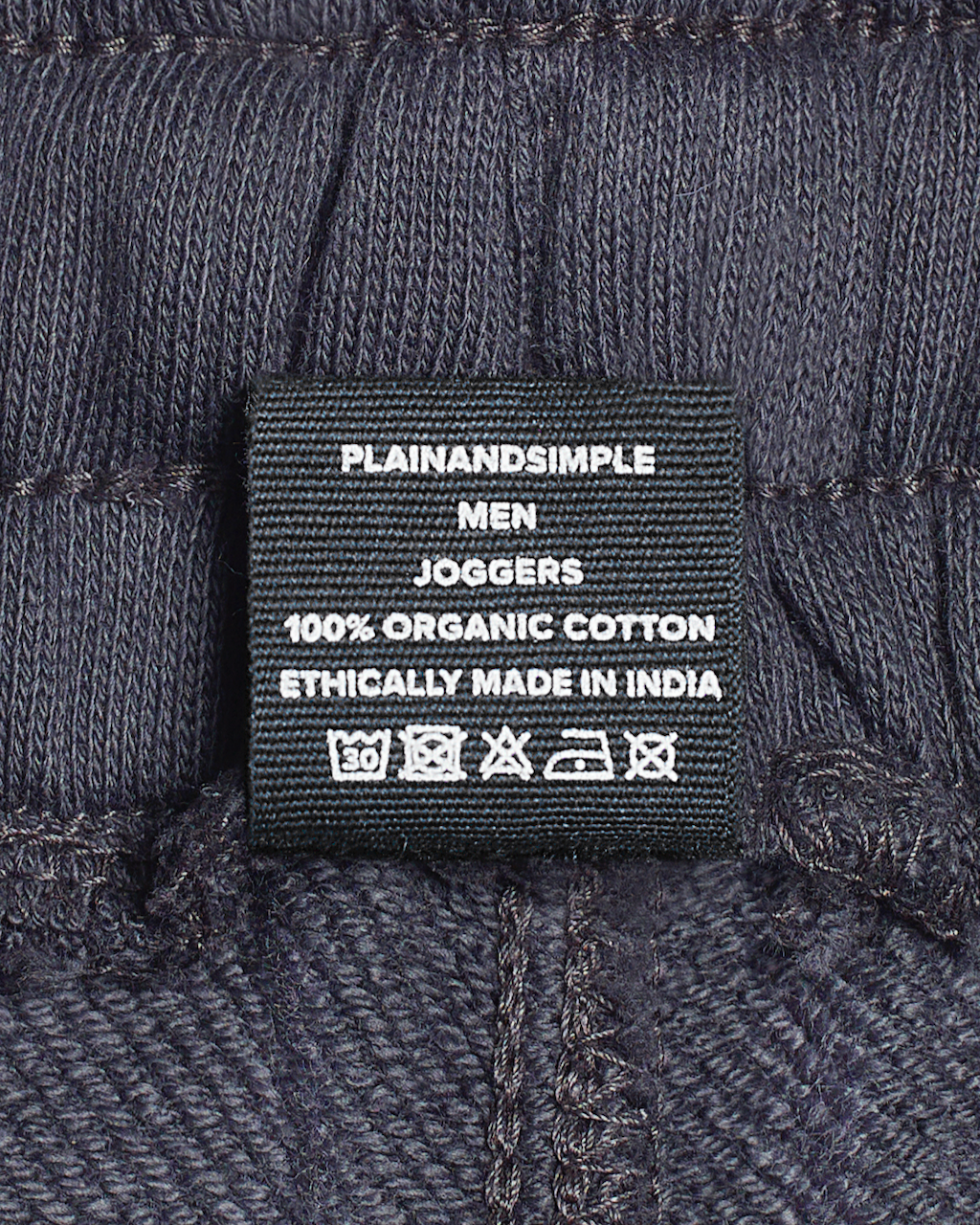 A close of the label in a pair of dark grey, organic cotton joggers.