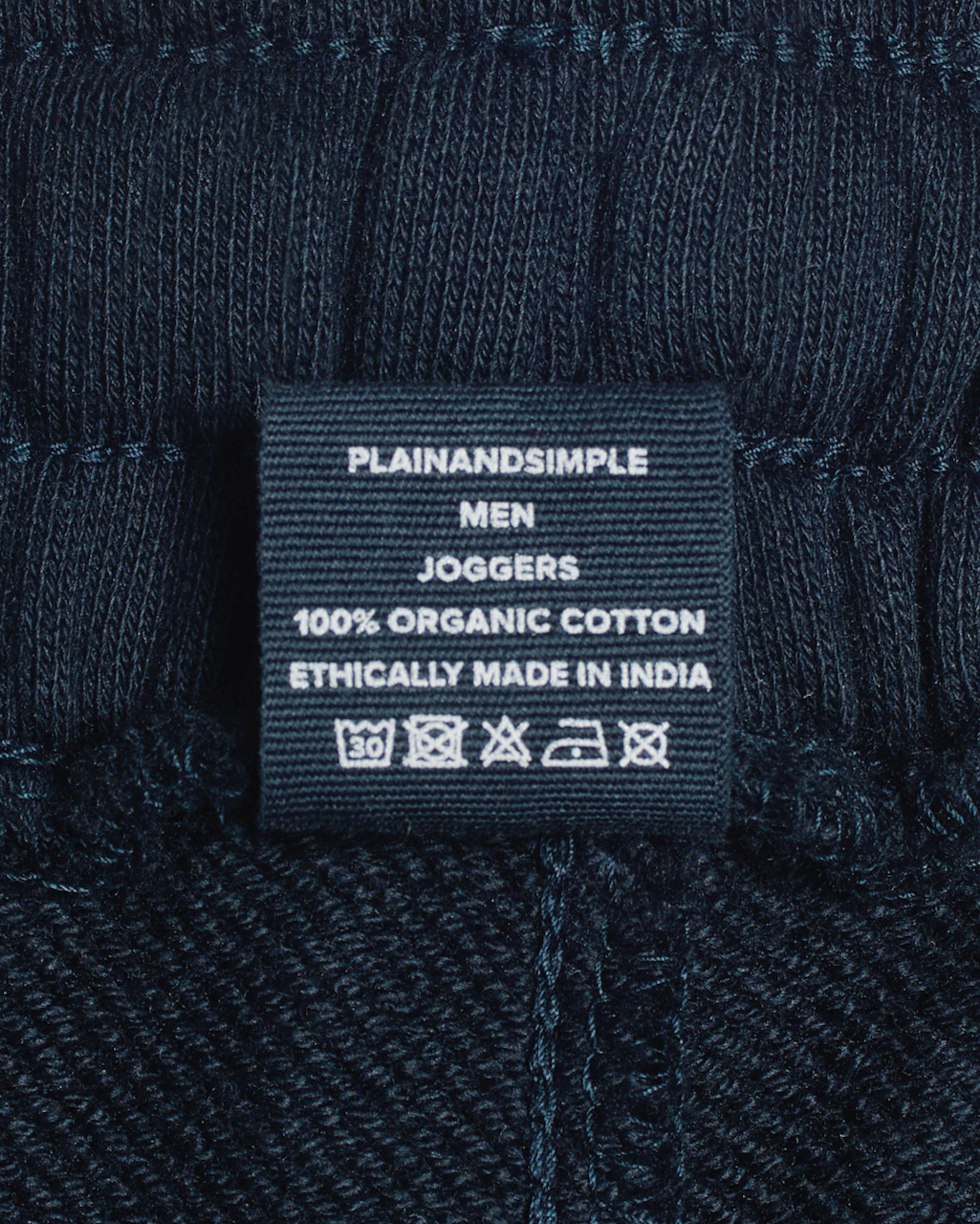 A close up of a label, for a pair of navy, organic cotton joggers.