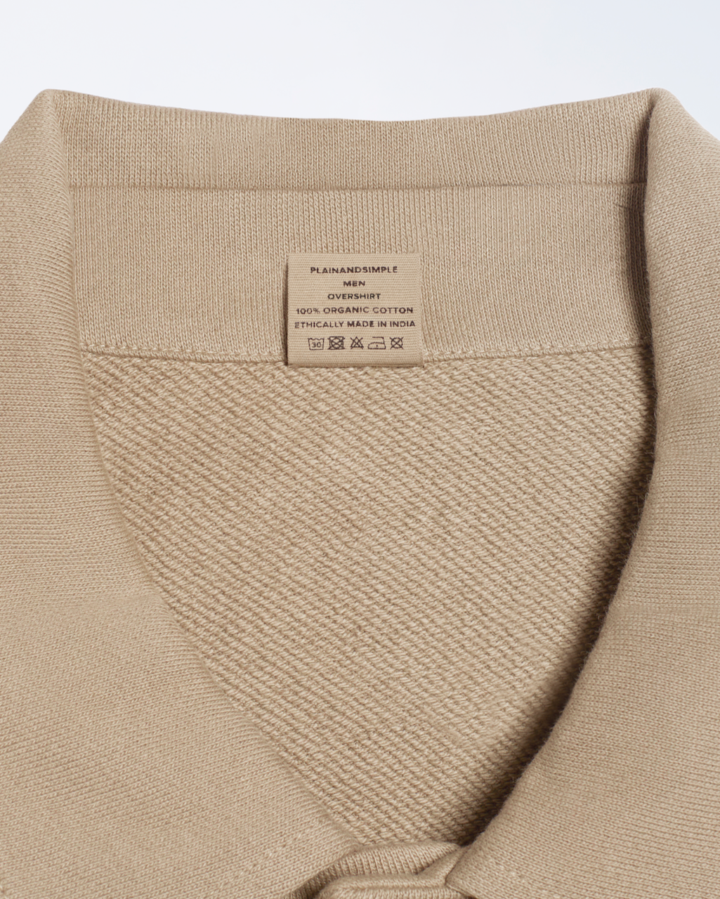 A close up of the neck label in a beige, organic cotton overshirt.