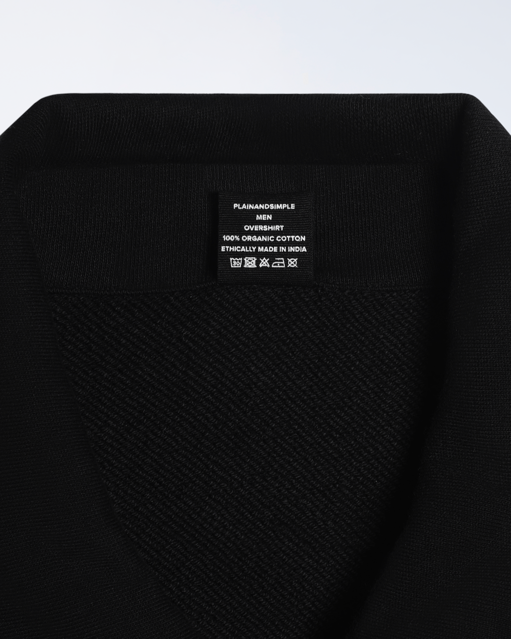 A close up of the neck label in a black, organic cotton overshirt.