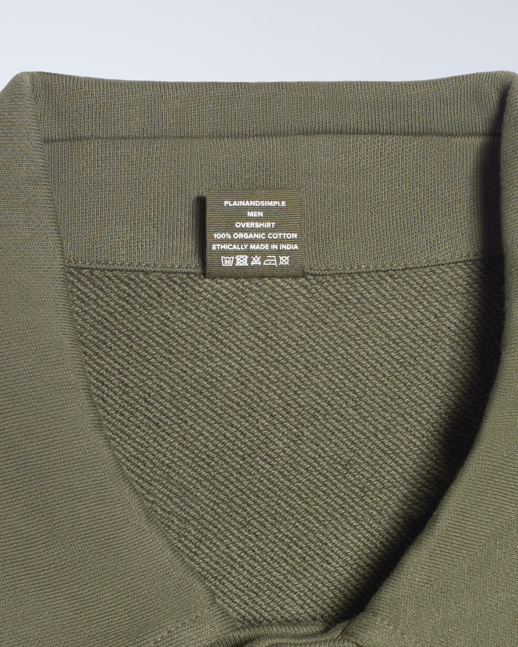A close up of the neck label in an olive, organic cotton overshirt.