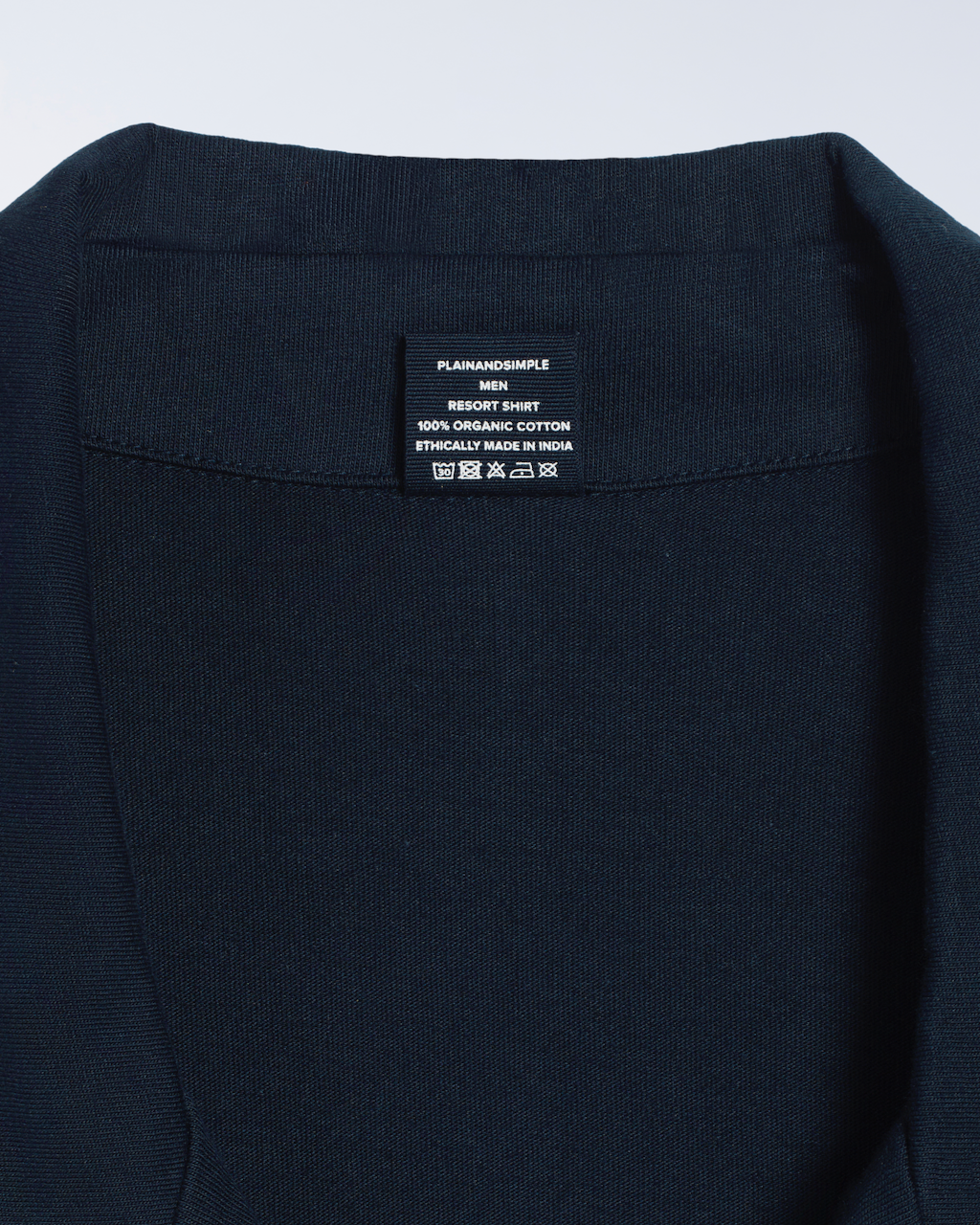 A close up of the neck label in a navy, organic cotton resort shirt.