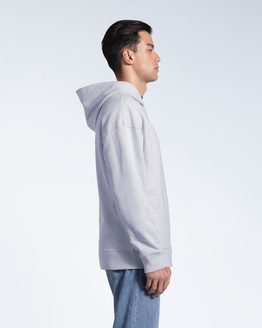 A man facing side on, modelling a grey oversized heavyweight organic cotton hoodie.
