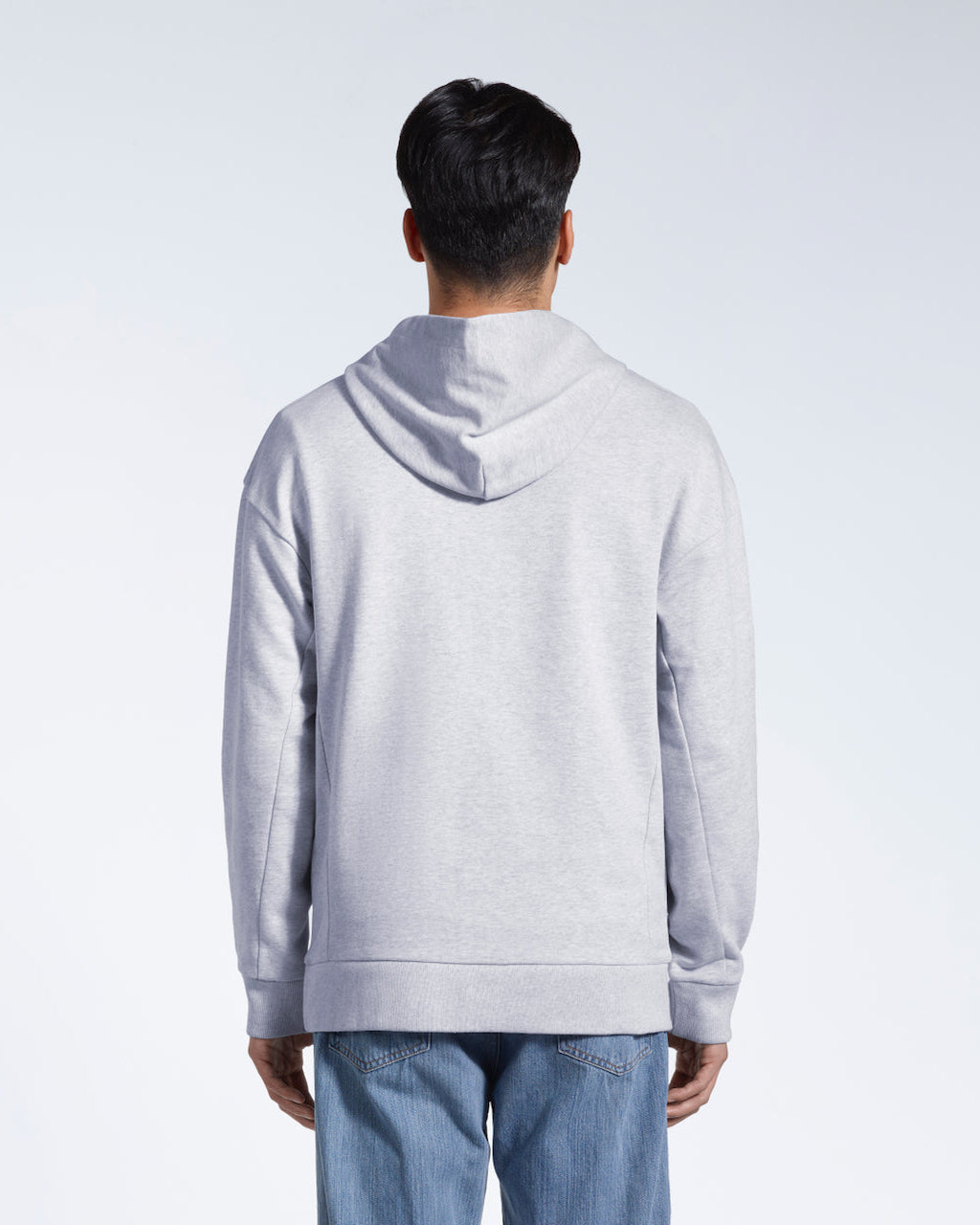 A man facing away from the camera with his arms by his sides, modelling a grey oversized heavyweight organic cotton hoodie.
