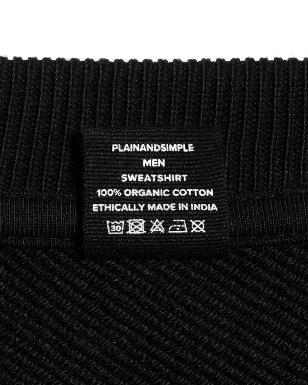 A close up of an neck label in a men's black oversized heavyweight organic cotton sweatshirt.