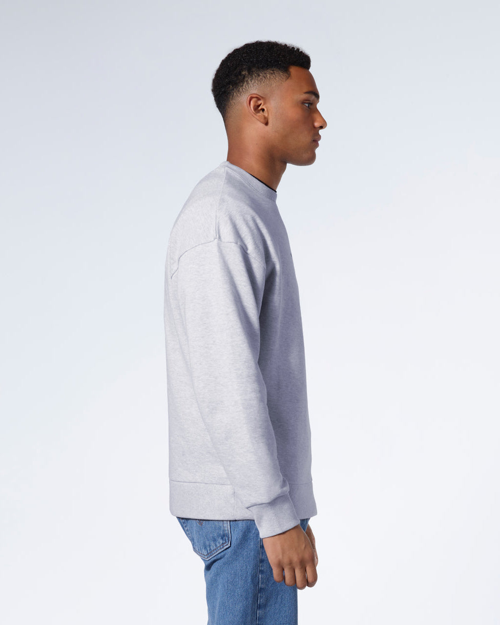 A man facing side on, modelling a grey oversized heavyweight organic cotton sweatshirt.
