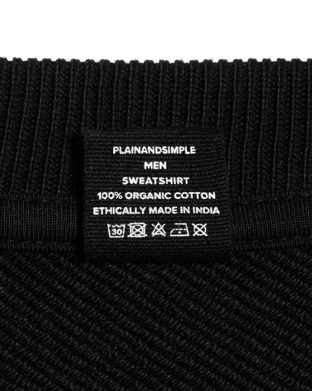 A close up of an neck label in a men's black oversized heavyweight organic cotton sweatshirt.