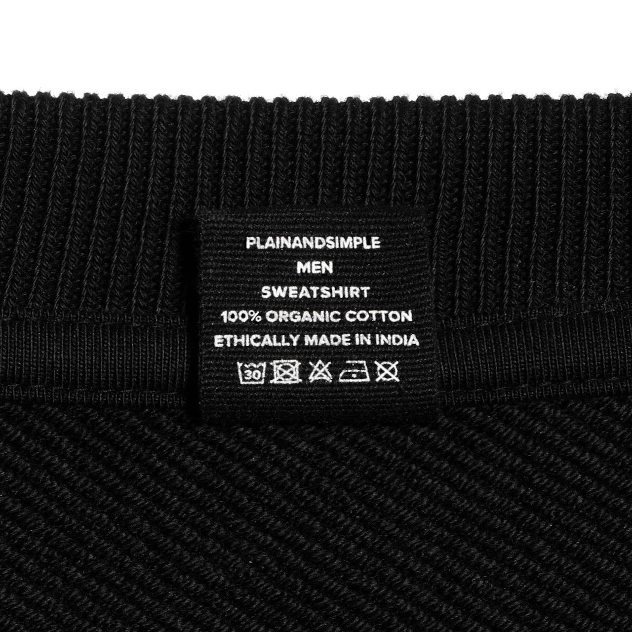 A close up of an neck label in a men's black oversized heavyweight organic cotton sweatshirt.