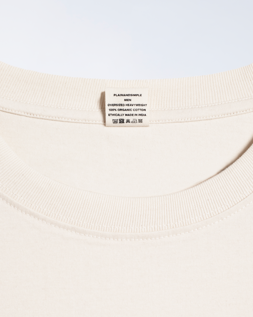 A close up of the neck label in a natural coloured, oversized, heavyweight, organic cotton t shirt.
