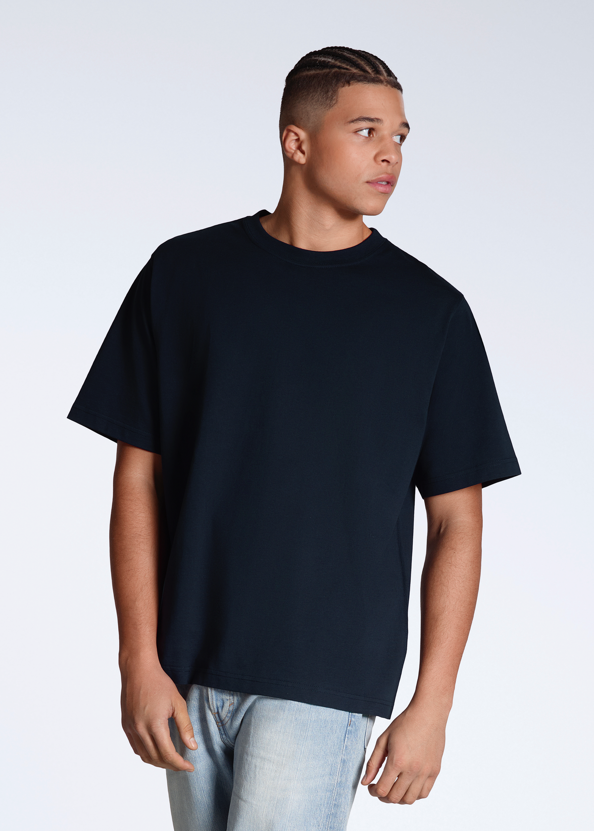 A man looking away from the camera, modelling a plain navy, oversized, organic cotton t shirt.