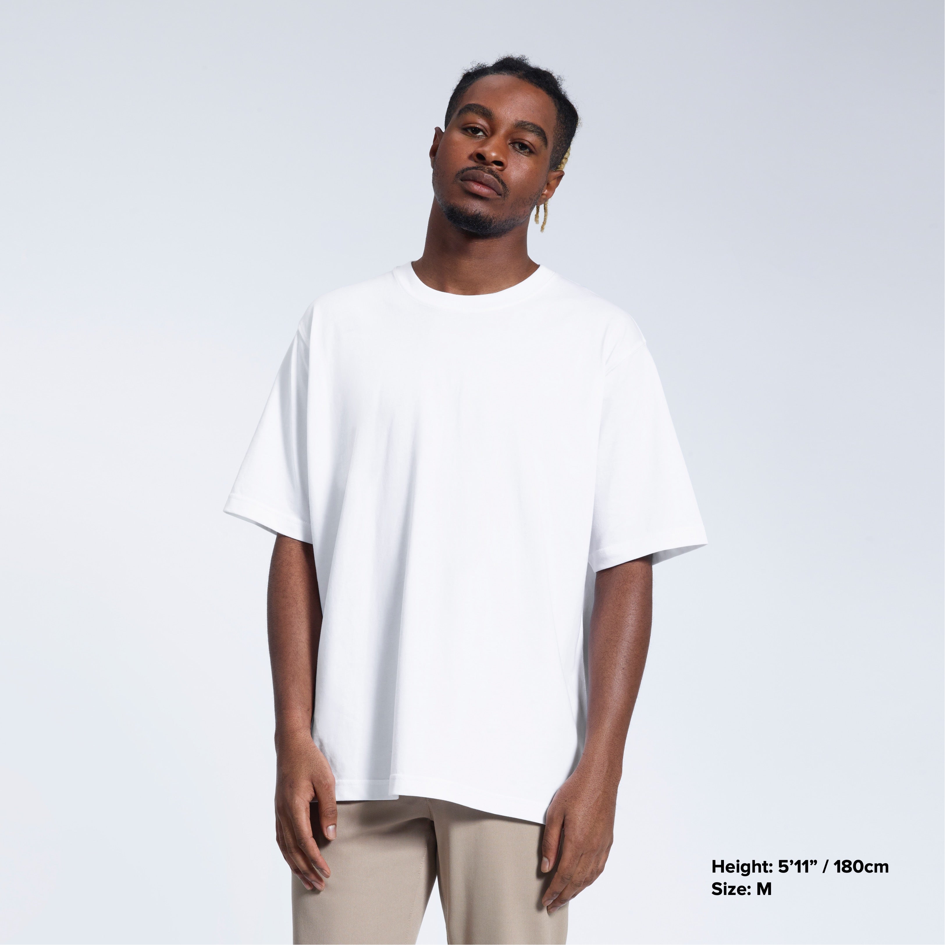 A man face on looking into the camera with his arms by his side, modelling a plain white oversized heavyweight organic cotton t shirt.