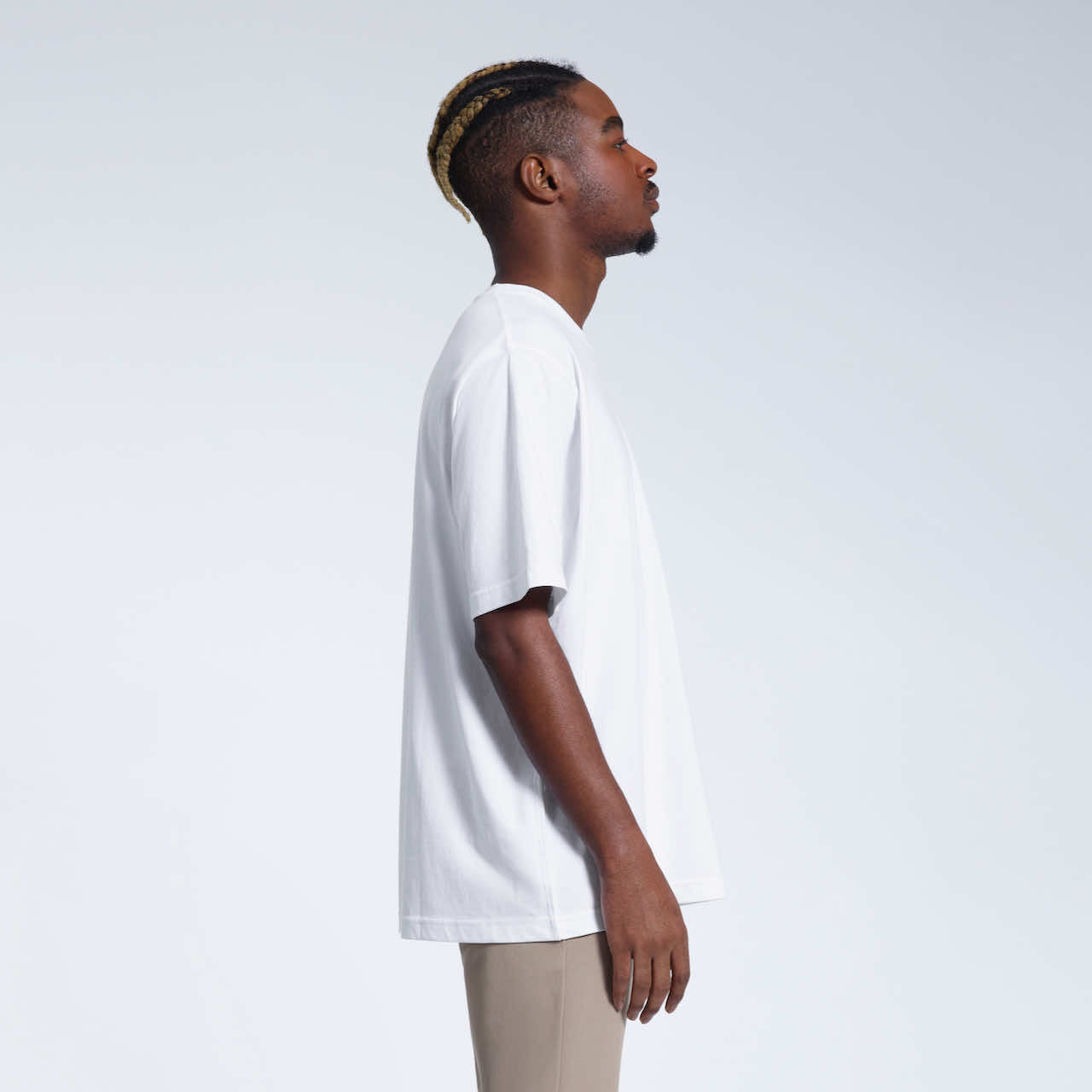 A man facing side on, modelling a plain white oversized heavyweight organic cotton t shirt.