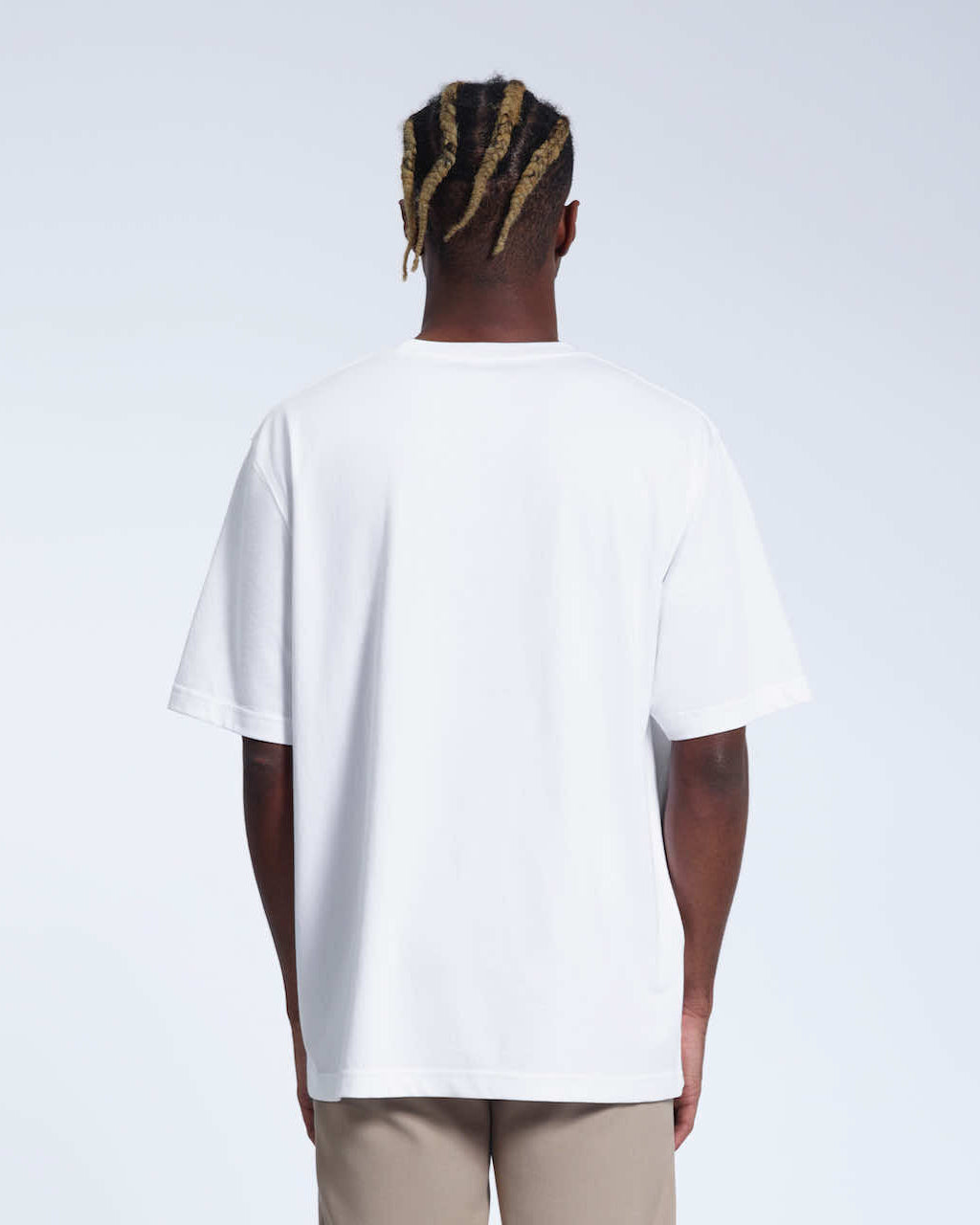 A man facing away from the camera with his arms by his side, modelling a plain white oversized heavyweight organic cotton t shirt.