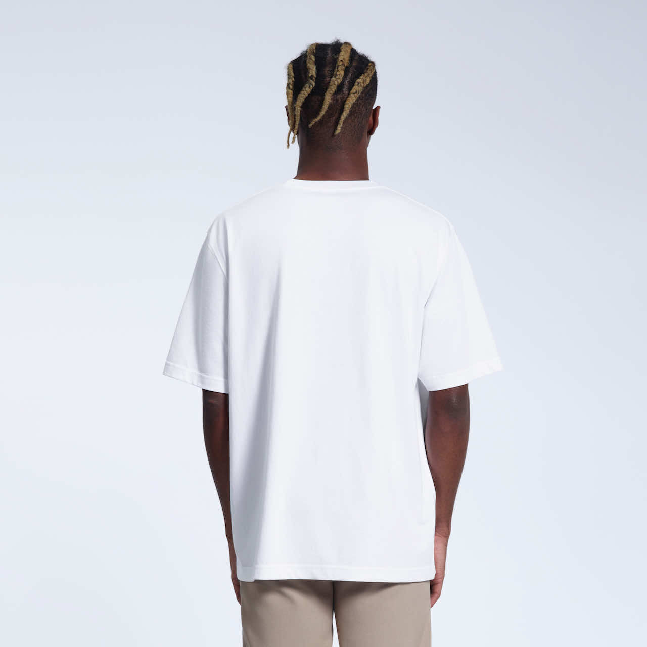 A man facing away from the camera with his arms by his side, modelling a plain white oversized heavyweight organic cotton t shirt.