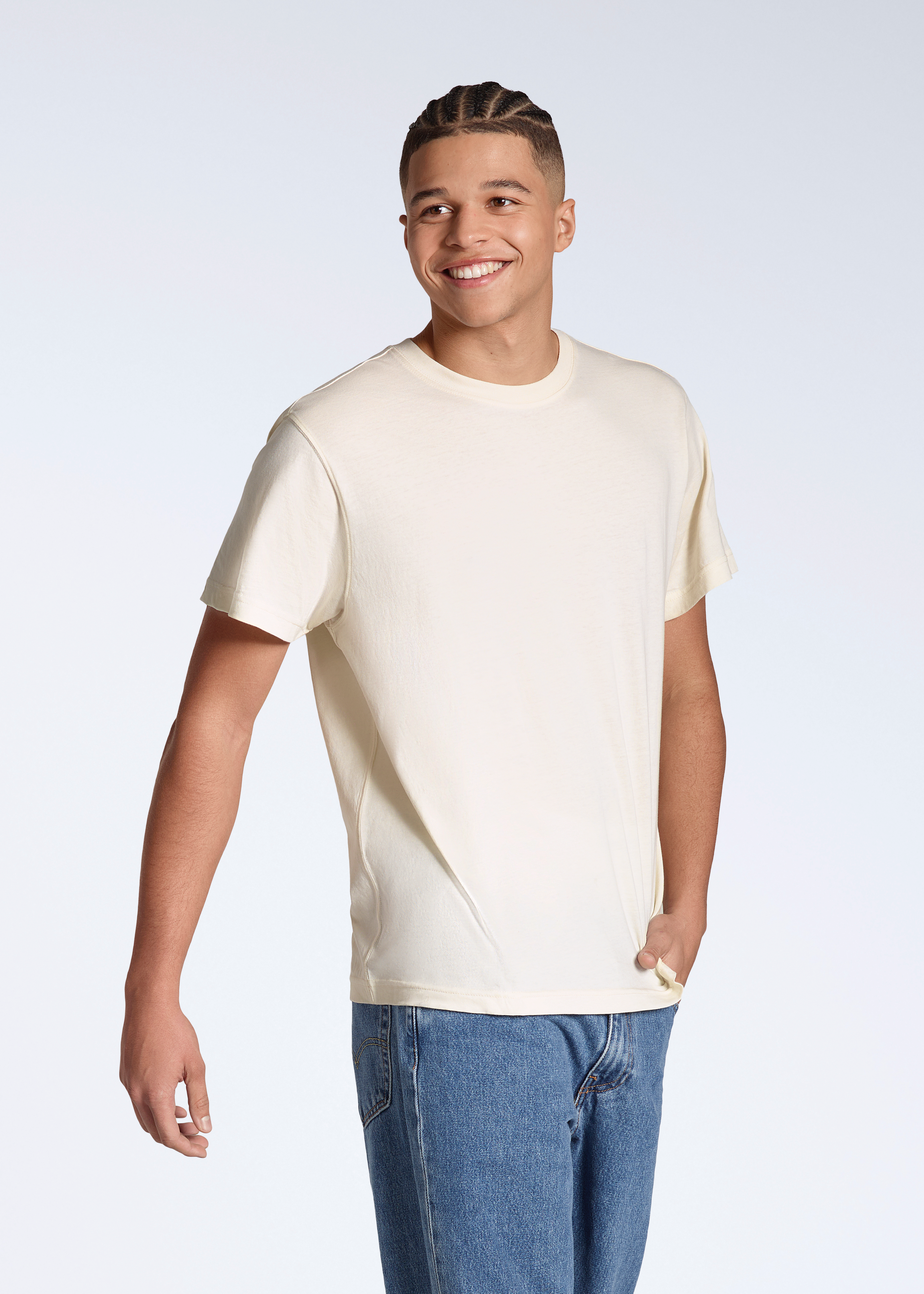 A man smiling with his hand in his pocket, modelling a plain, natural coloured, organic cotton t shirt.