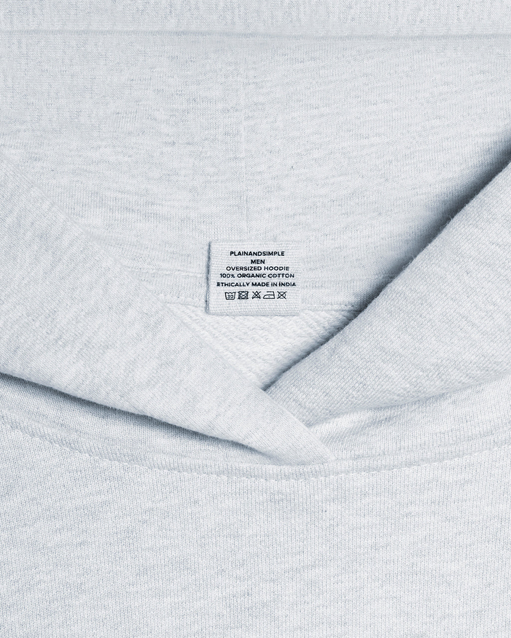 A close up of a neck label in a men's grey, oversized, organic cotton hoodie.