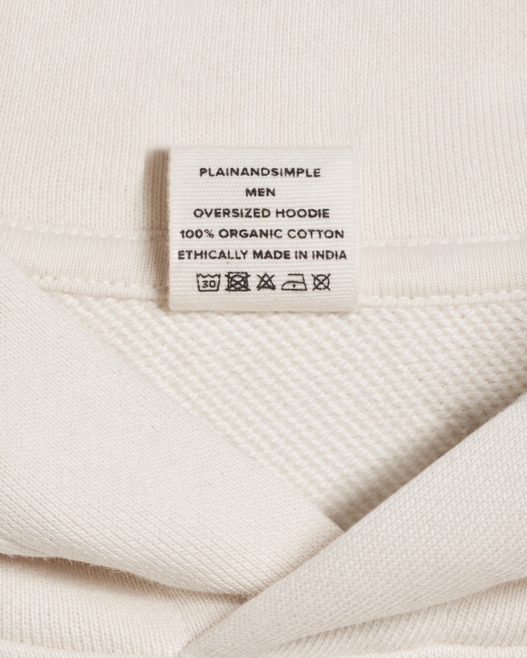 A close up of the neck label in a natural coloured, oversized, organic cotton hoodie.