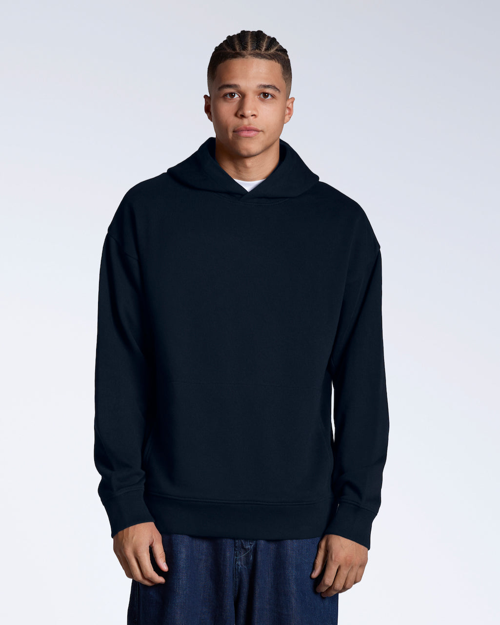 A man facing front on looking into the camera with his arms by his sides, modelling a navy oversized organic cotton hoodie.
