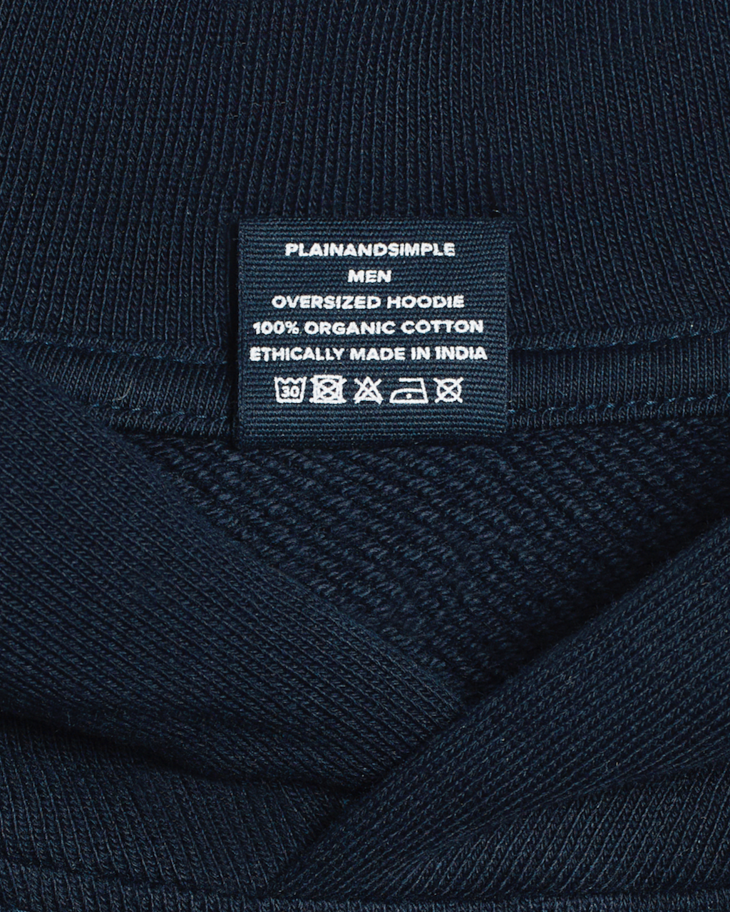 A close up of the neck label in a navy, oversized, organic cotton hoodie.