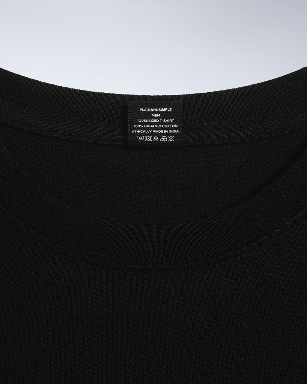 A close up of a neck label in a men's black, oversized, organic cotton t shirt.