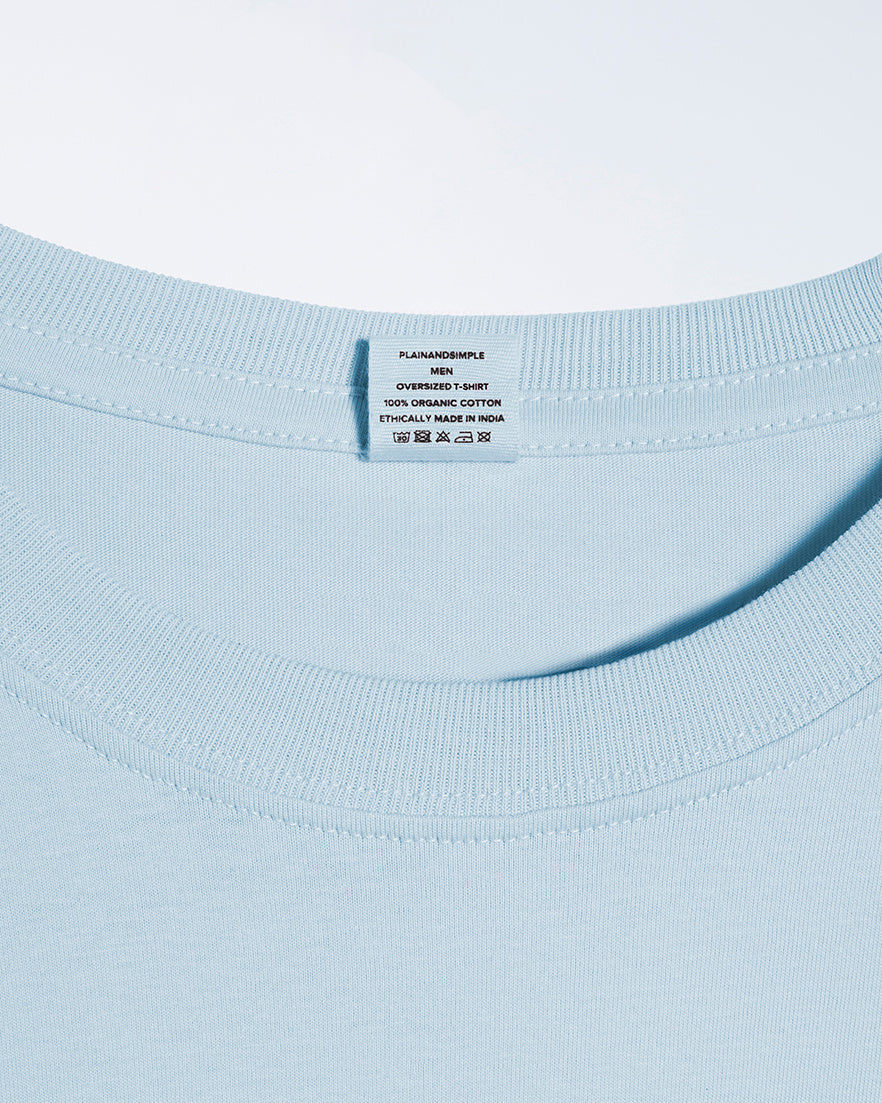 A close up of a neck label in a men's dove blue, oversized, organic cotton t shirt.