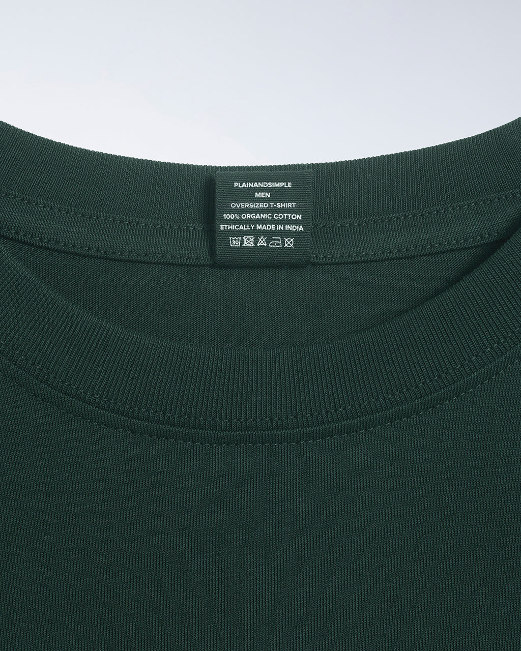 A close up of a neck label in a men's green, oversized, organic cotton t shirt.
