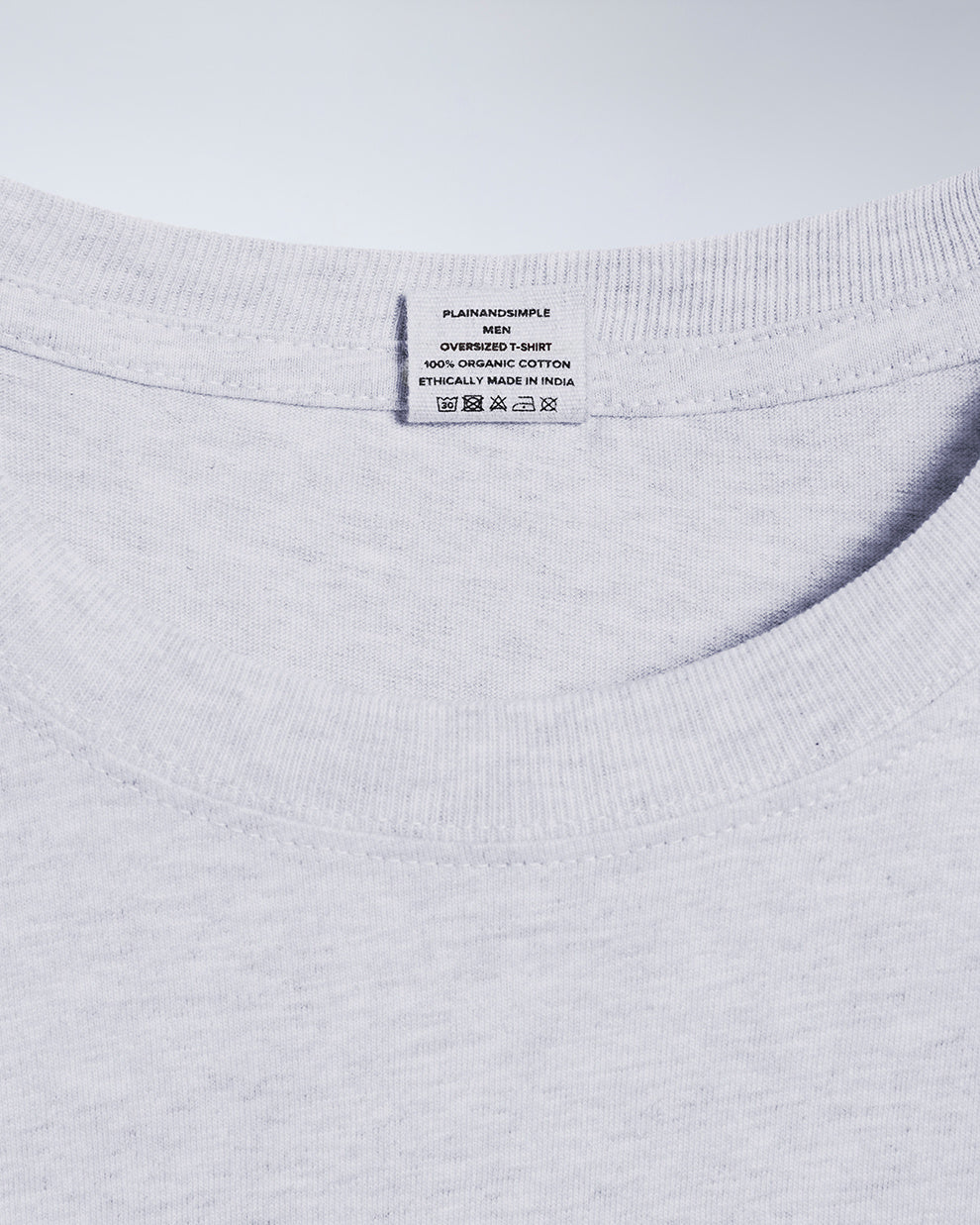 A close up of a neck label in a men's grey, oversized, organic cotton t shirt.
