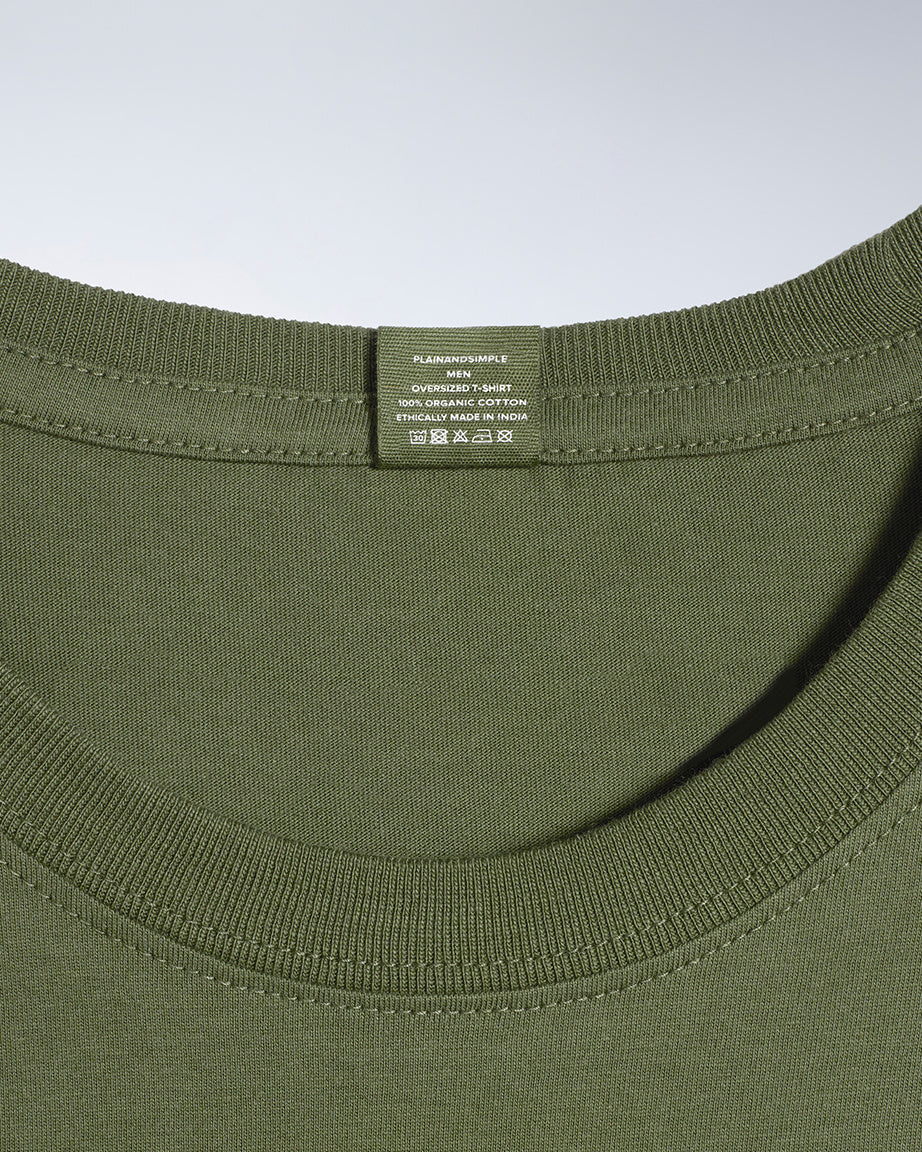 A close up of a neck label in a men's khaki green, oversized, organic cotton t shirt.