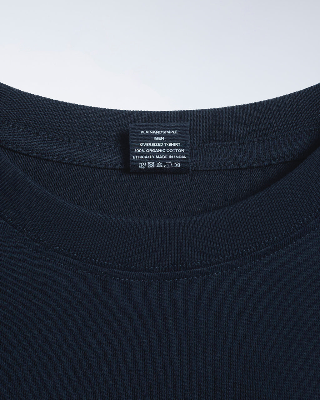 A close up of a neck label in a men's navy, oversized, organic cotton t shirt.