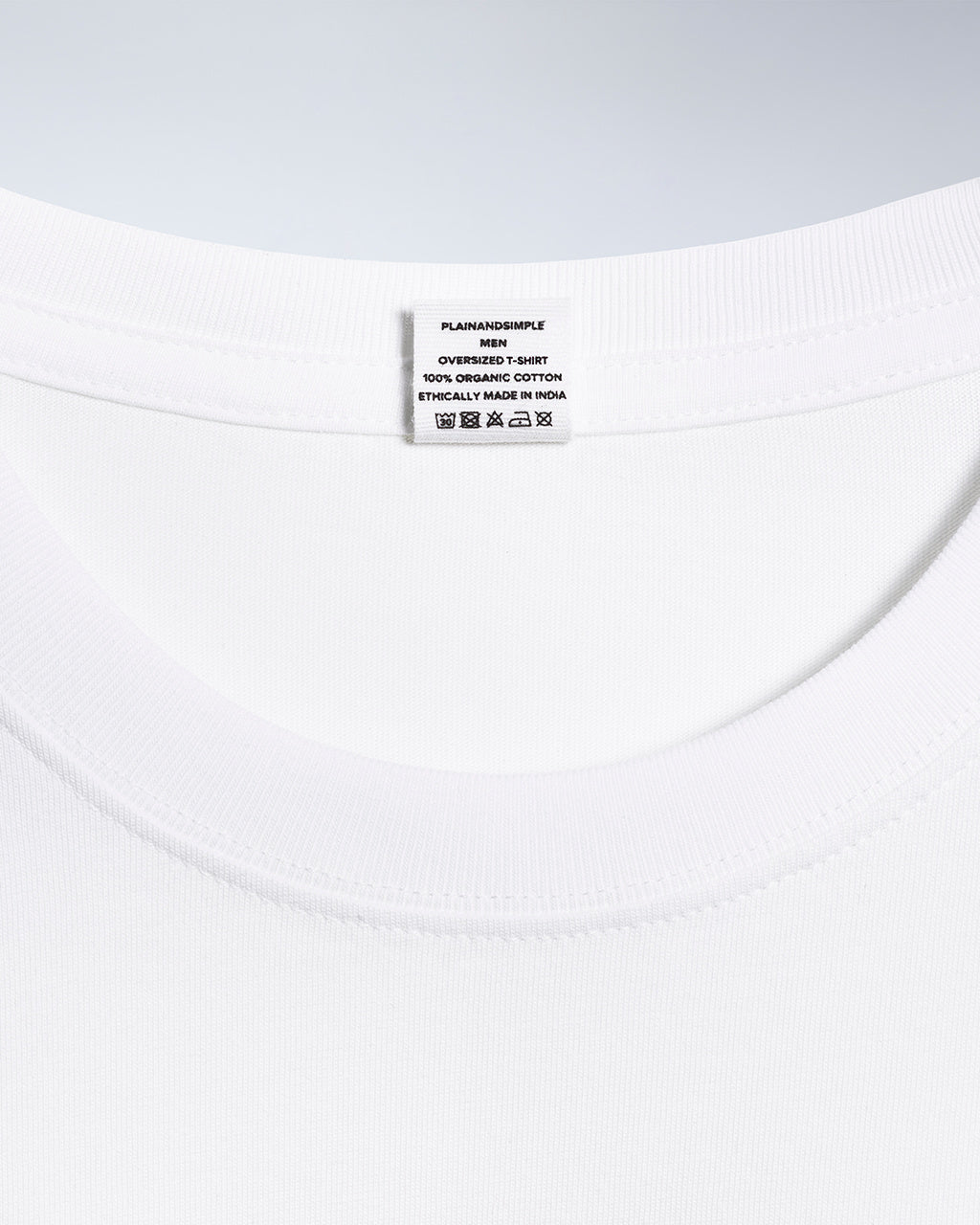 A close up of a neck label in a men's white, oversized, organic cotton t shirt.