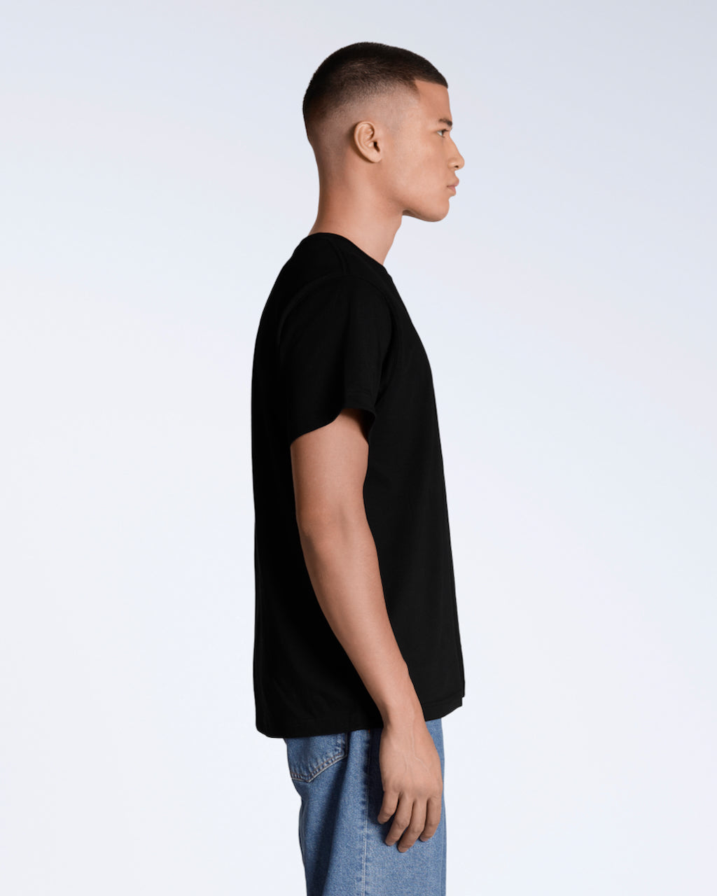 A man facing side on, modelling a plain black short sleeve organic cotton t shirt.