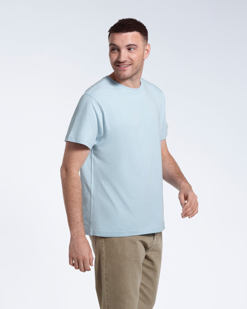 A man smiling looking back, modelling a plain light blue short sleeve organic cotton t shirt.