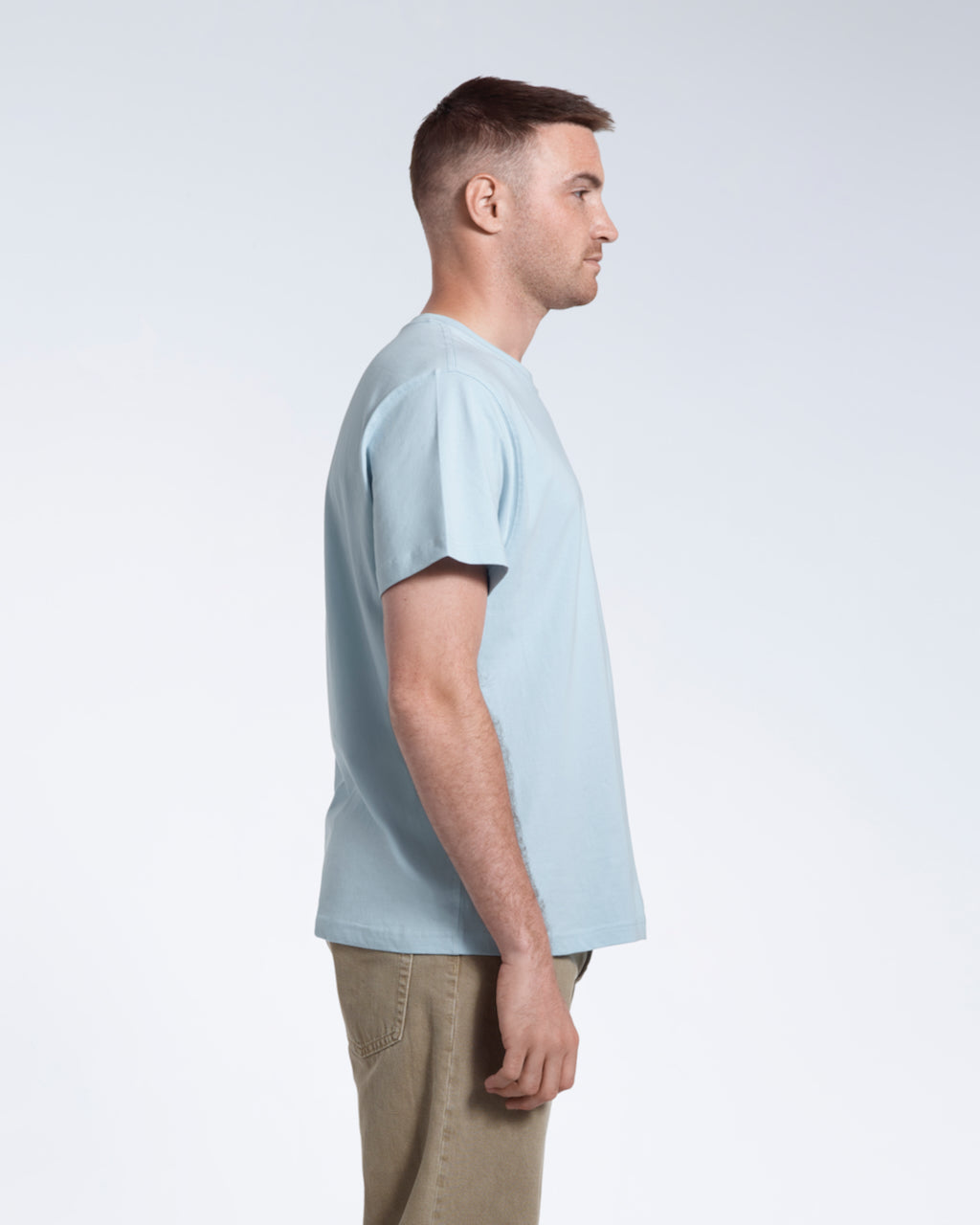 A man facing side on, modelling a plain light blue short sleeve organic cotton t shirt.