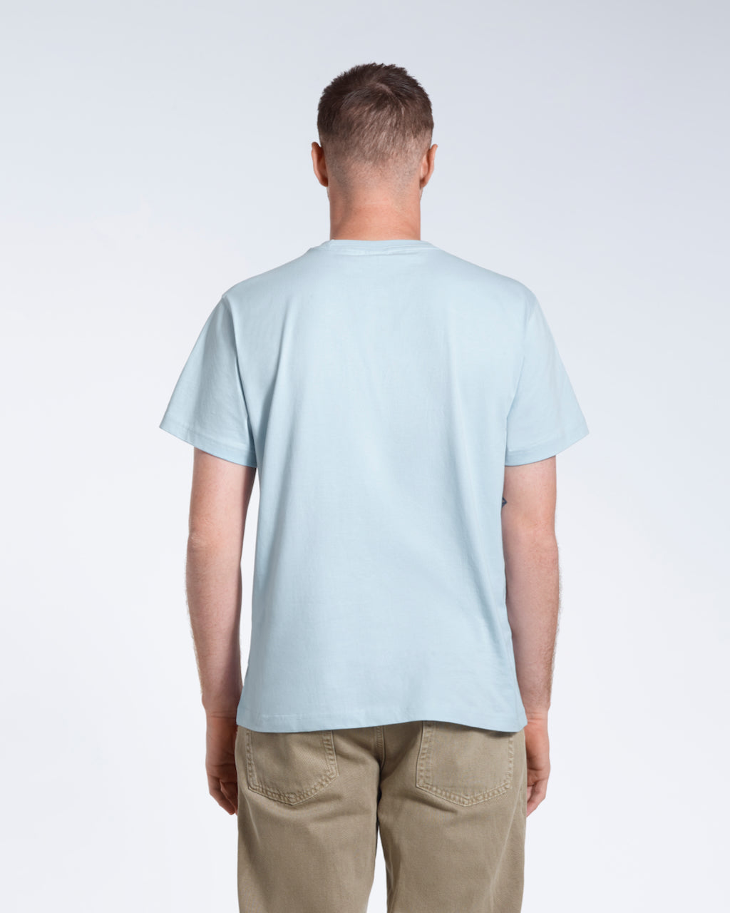 A man facing away from the camera, modelling a plain blue short sleeve organic cotton t shirt.