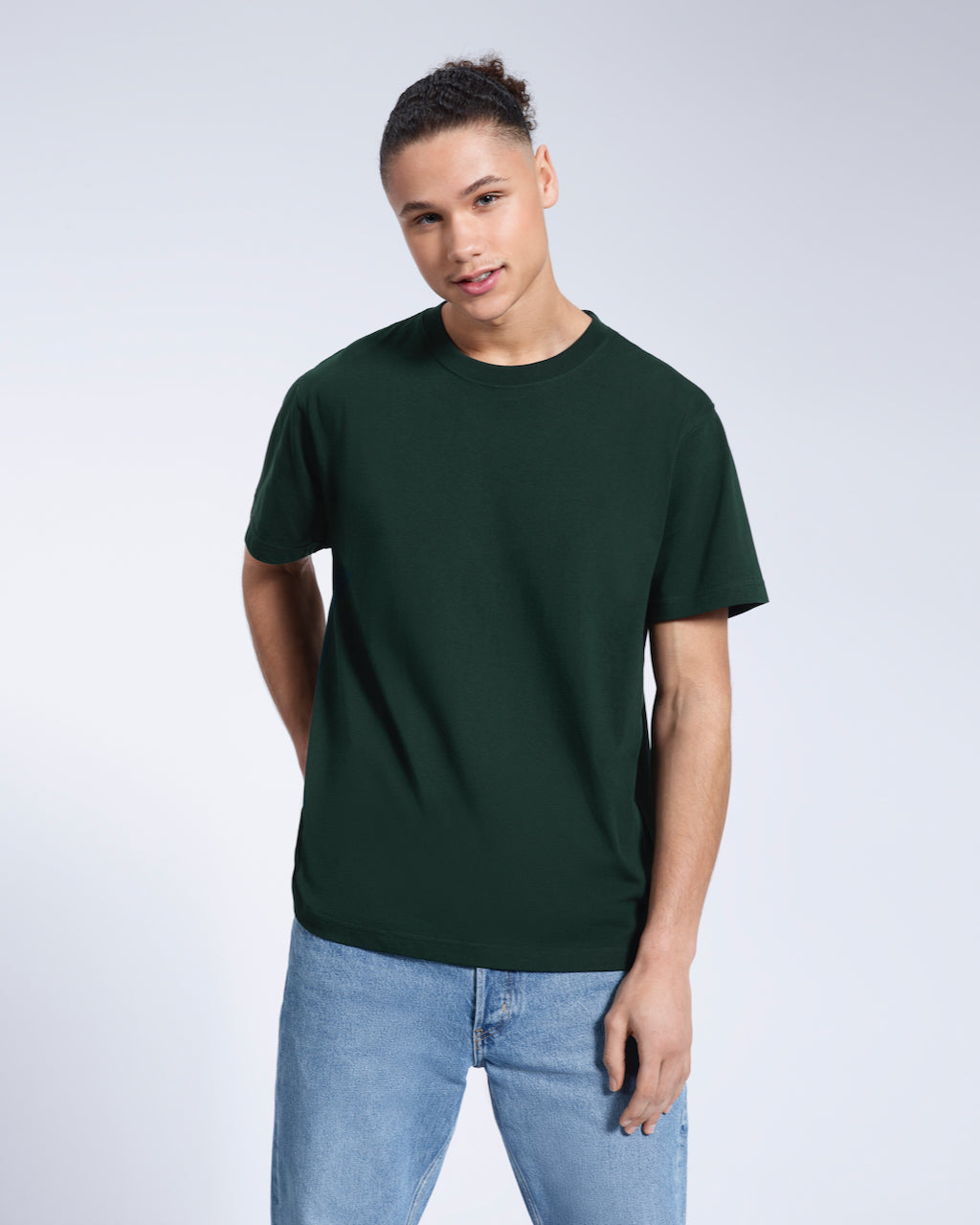 A man smiling into the camera, modelling a plain green short sleeve organic cotton t shirt.