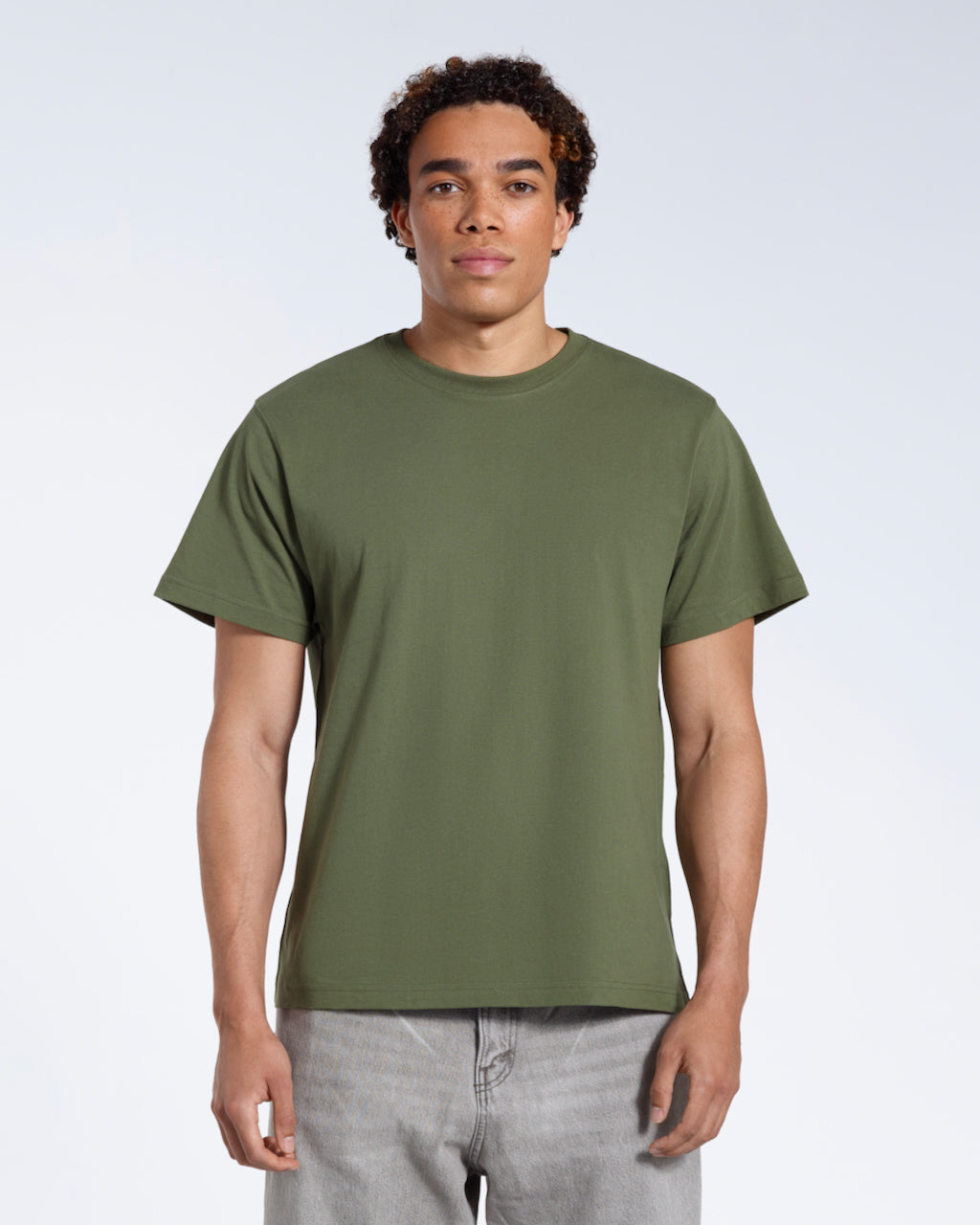 A man facing front on looking into the camera, modelling a plain khaki green short sleeve organic cotton t shirt.
