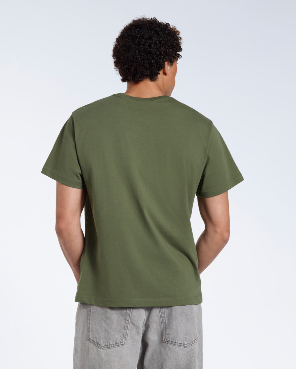 A man facing away from the camera, modelling a plain khaki green short sleeve organic cotton t shirt.