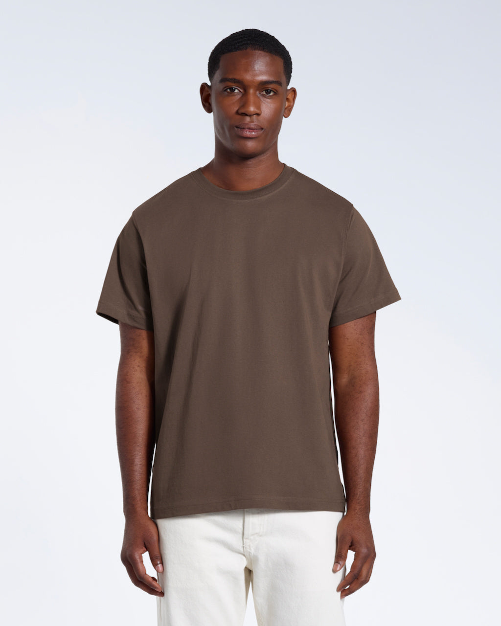 A man facing front on looking into the camera, modelling a plain dark khaki short sleeve organic cotton t shirt.