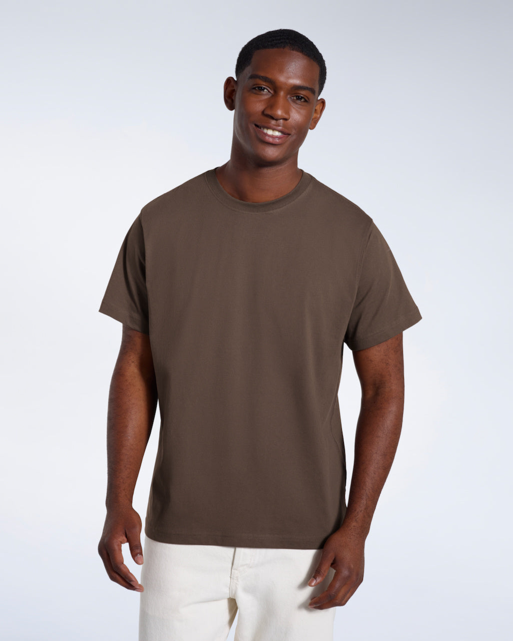 A man smiling looking into the camera, modelling a plain dark khaki short sleeve organic cotton t shirt.