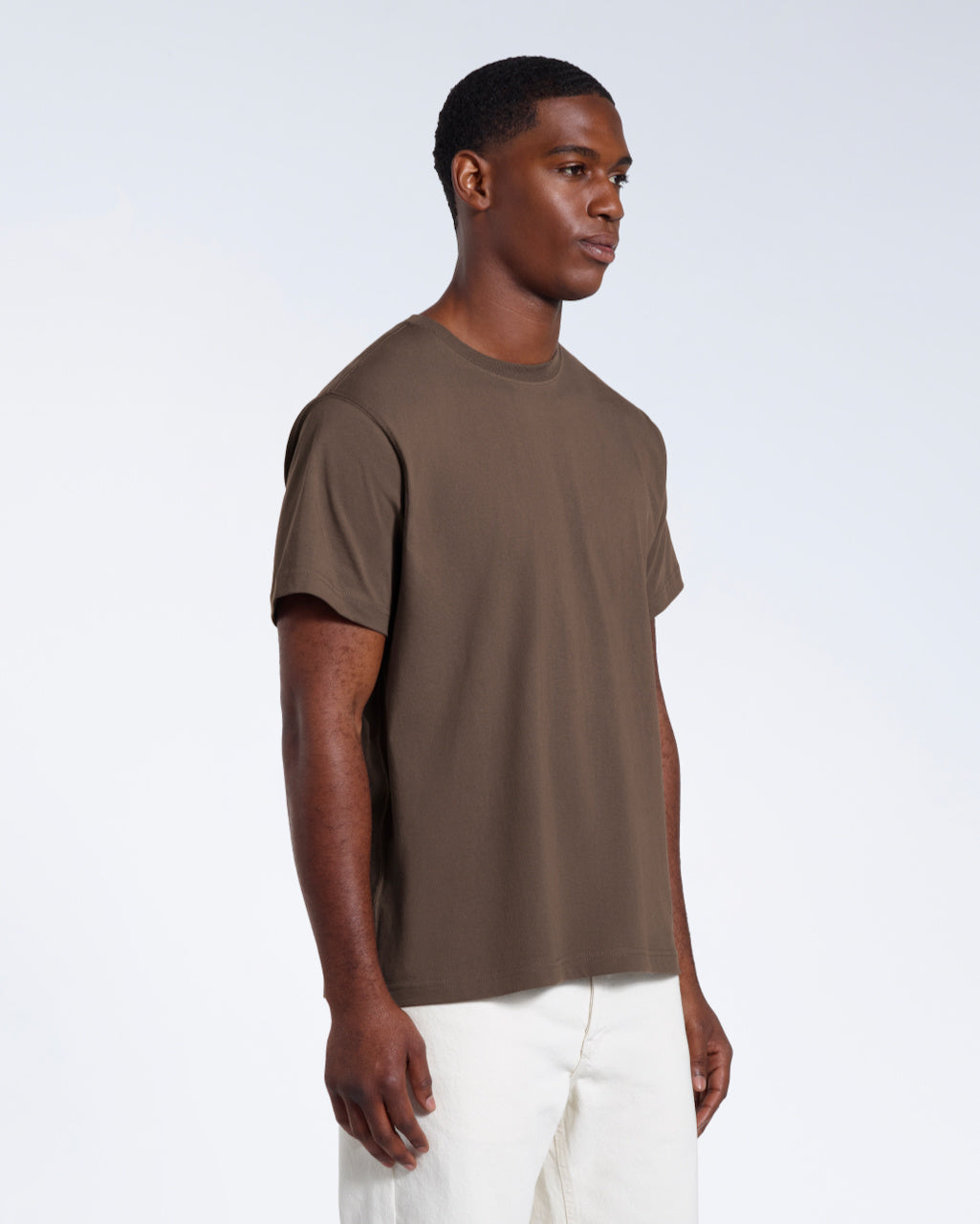 A man at an angle with his arms by his sides, modelling a plain dark khaki short sleeve organic cotton t shirt.