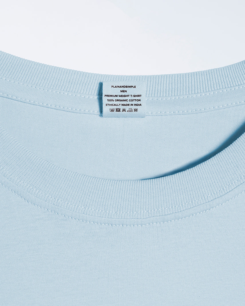 A close up of a neck label in a men's light blue short sleeve crew neck organic cotton t shirt.