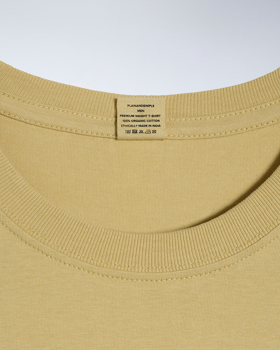 A close up of a neck label in a men's light khaki short sleeve crew neck organic cotton t shirt.