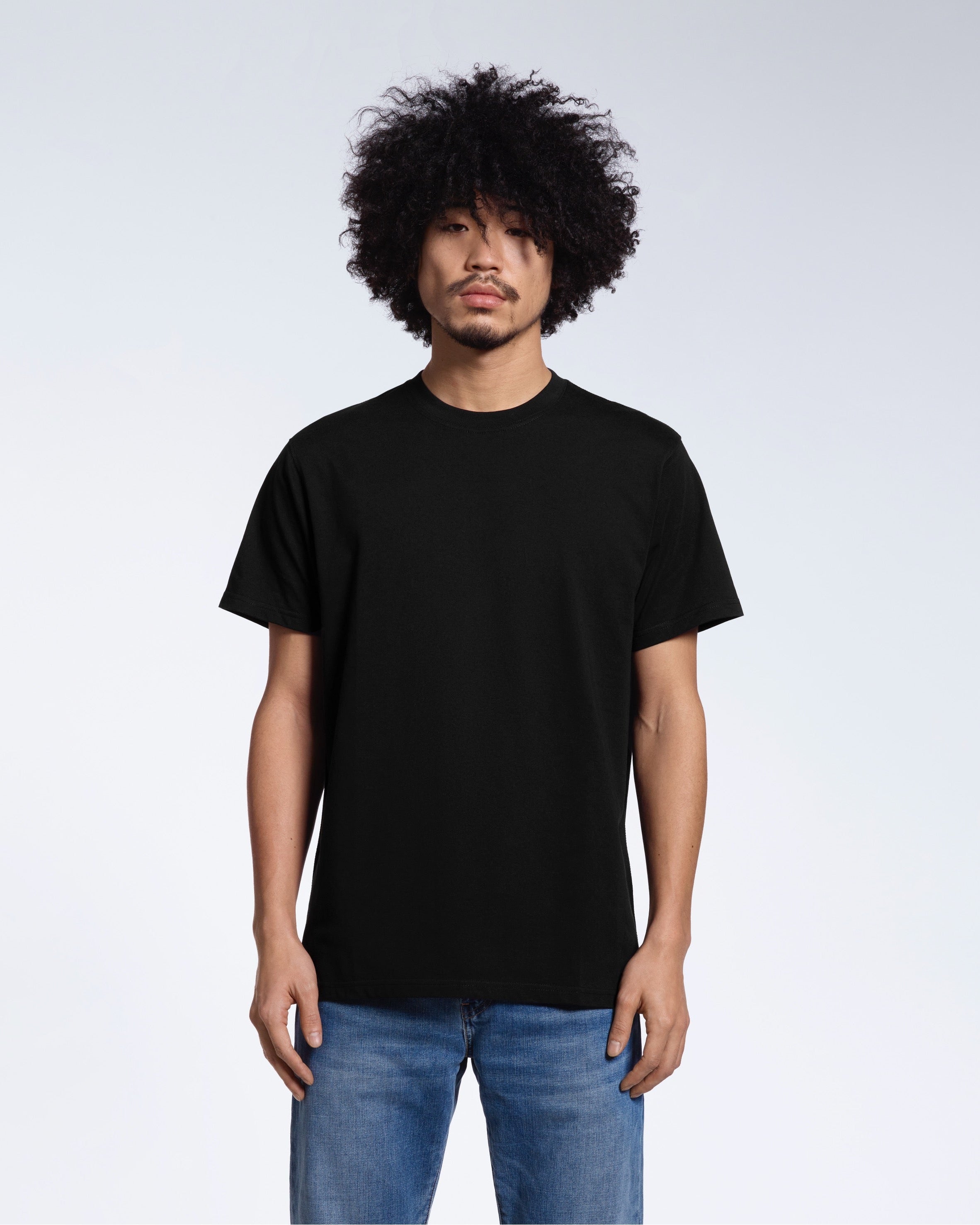A man facing front on looking into the camera, modelling a plain black short sleeve organic cotton t shirt.