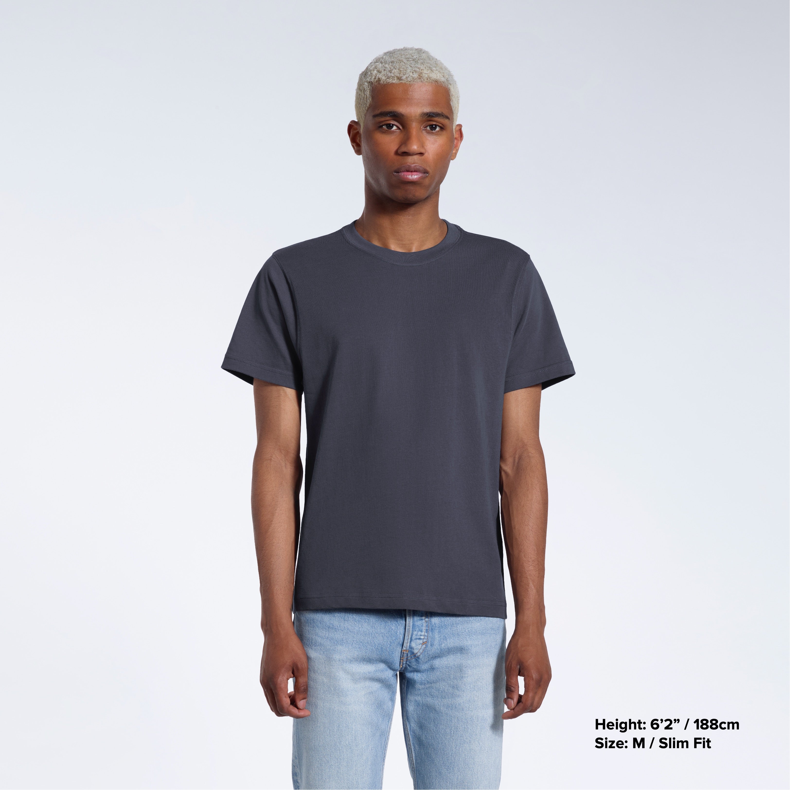 A man facing front on looking into the camera, modelling a plain dark grey short sleeve organic cotton t shirt.